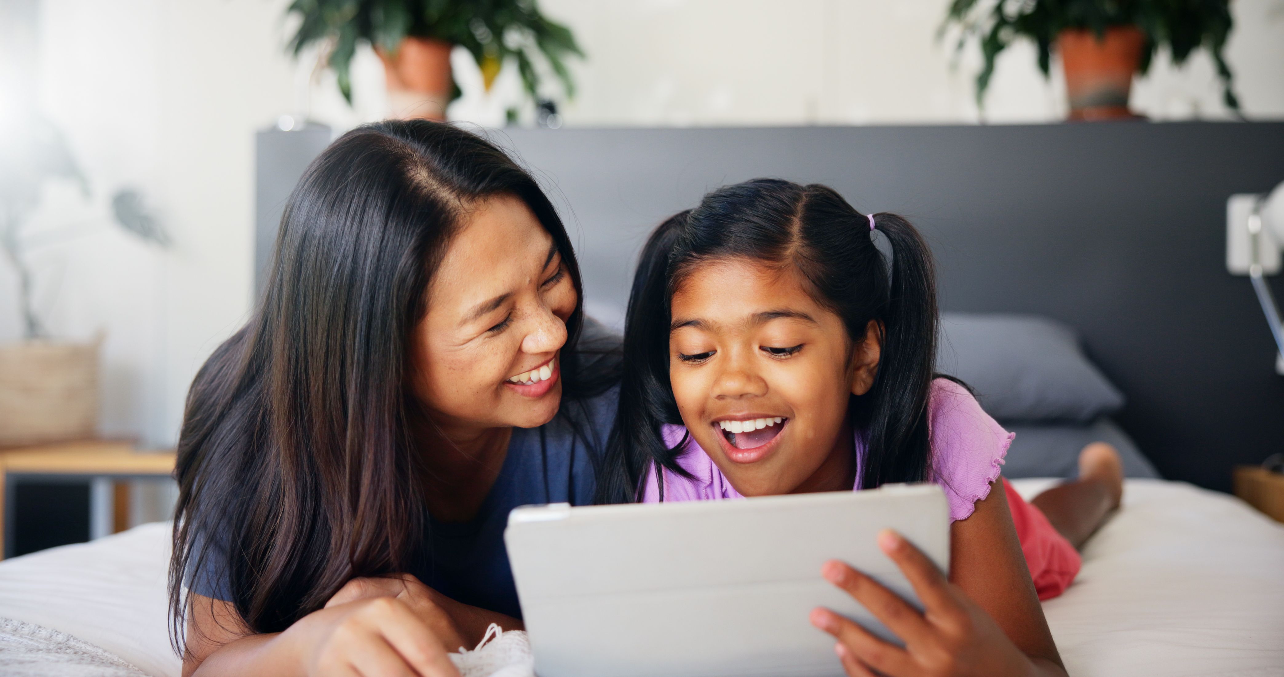 Mother, child and relax with tablet on bed for playing educational games, streaming subscribe and bonding. Happy family, woman and girl with digital app in home for watching cartoon or online scroll