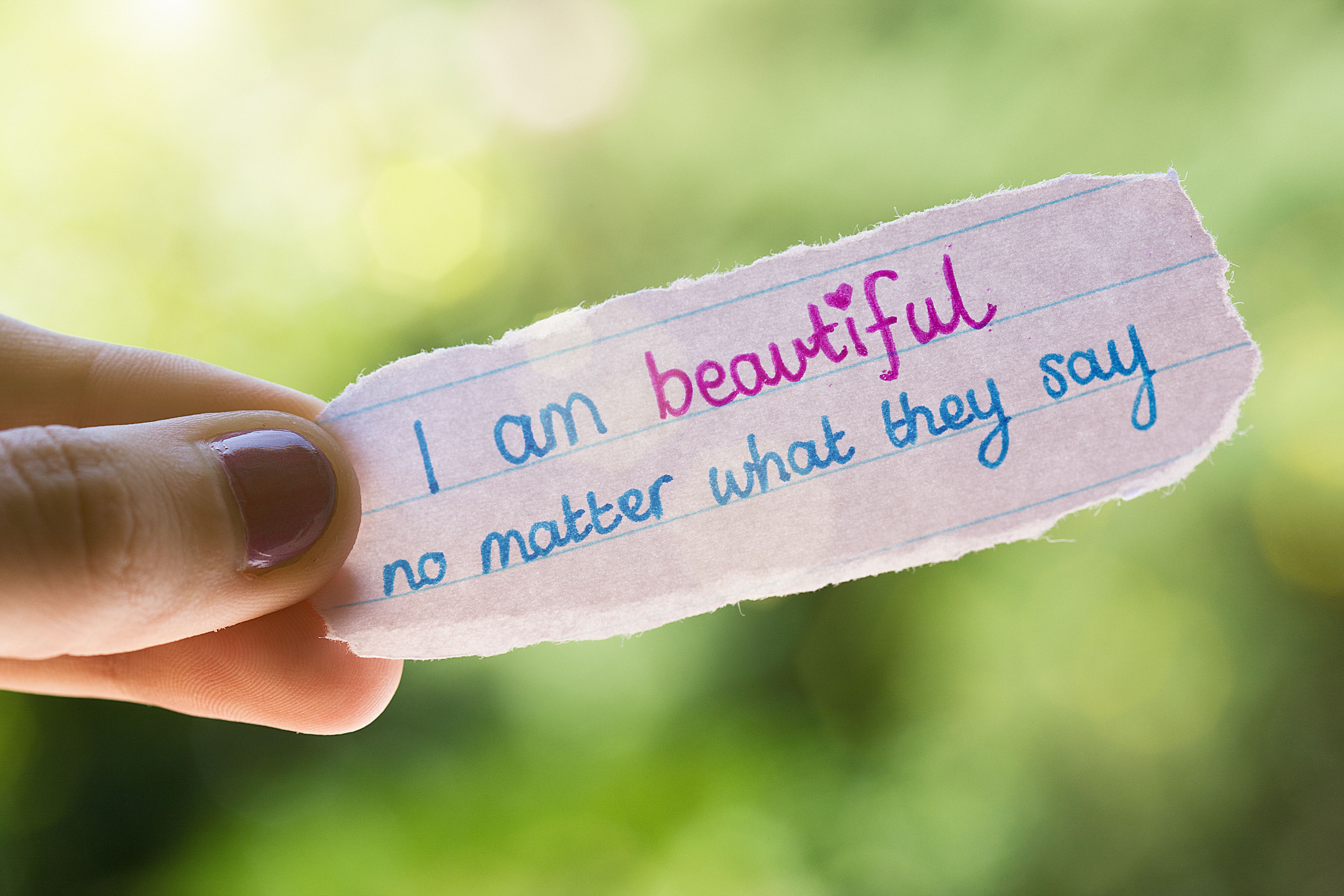 Hand-written self-affirming note held by woman