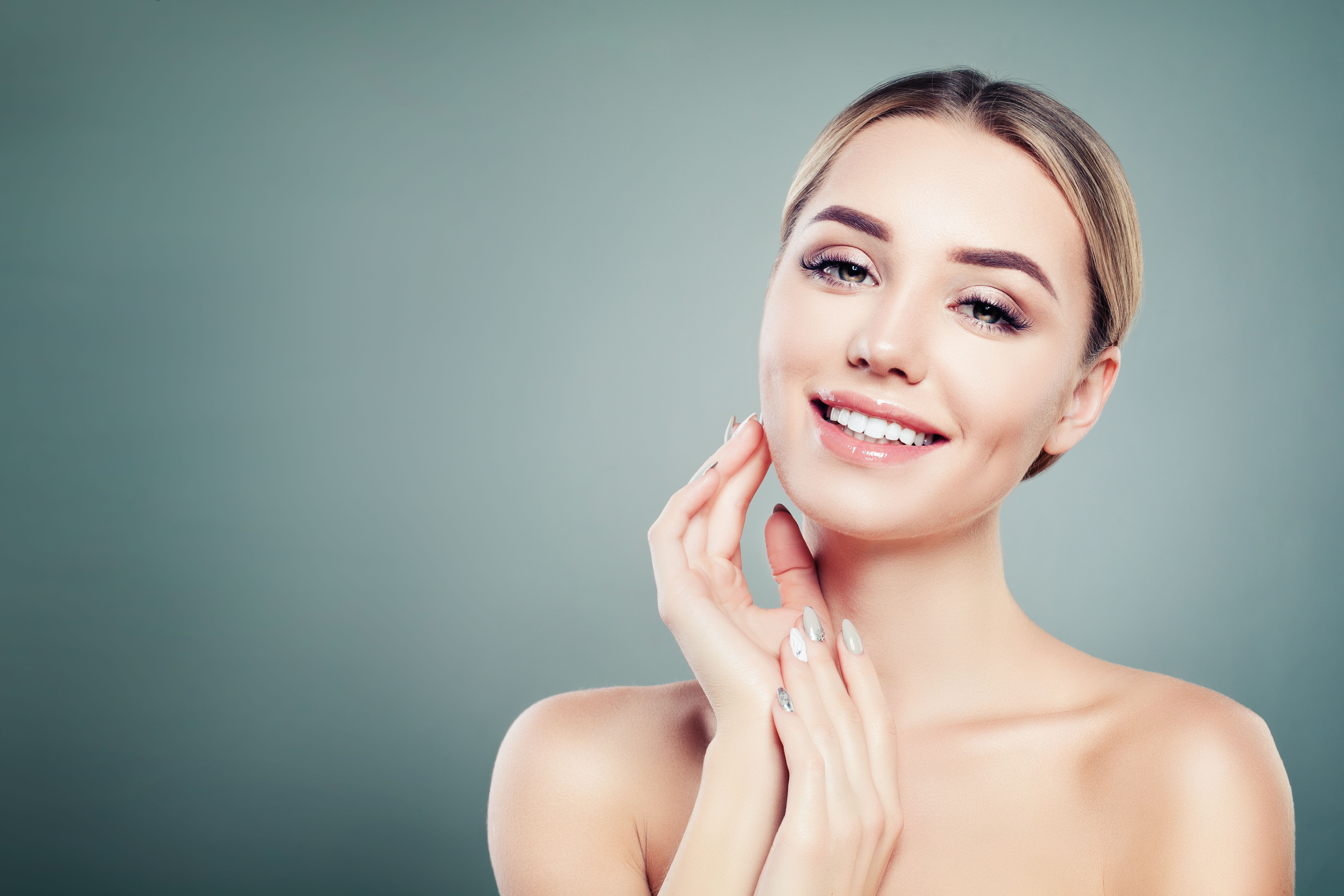 Healthy face young smiling woman on blue background with copy space