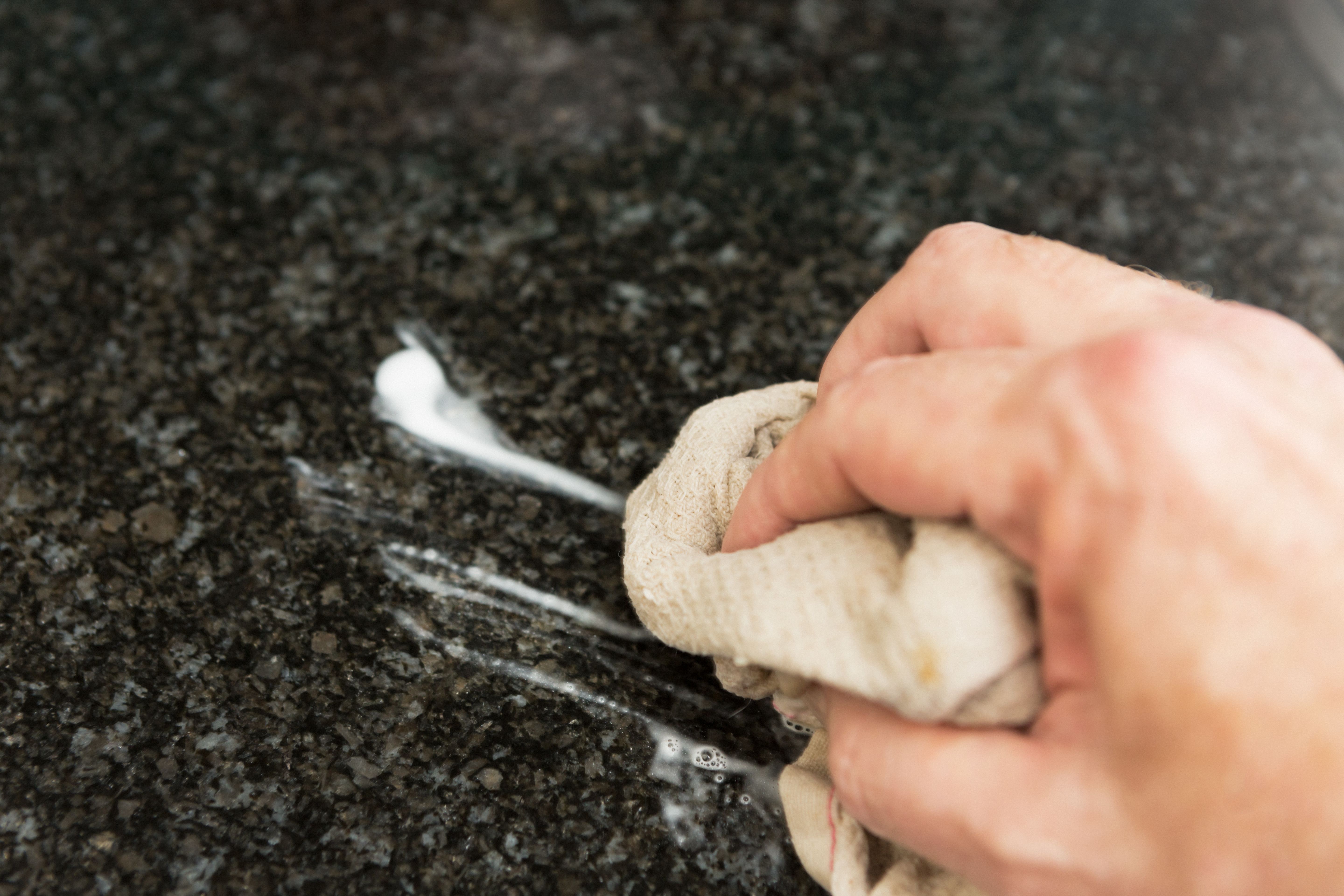 Man's hand cleaning surface in domestic kitchen