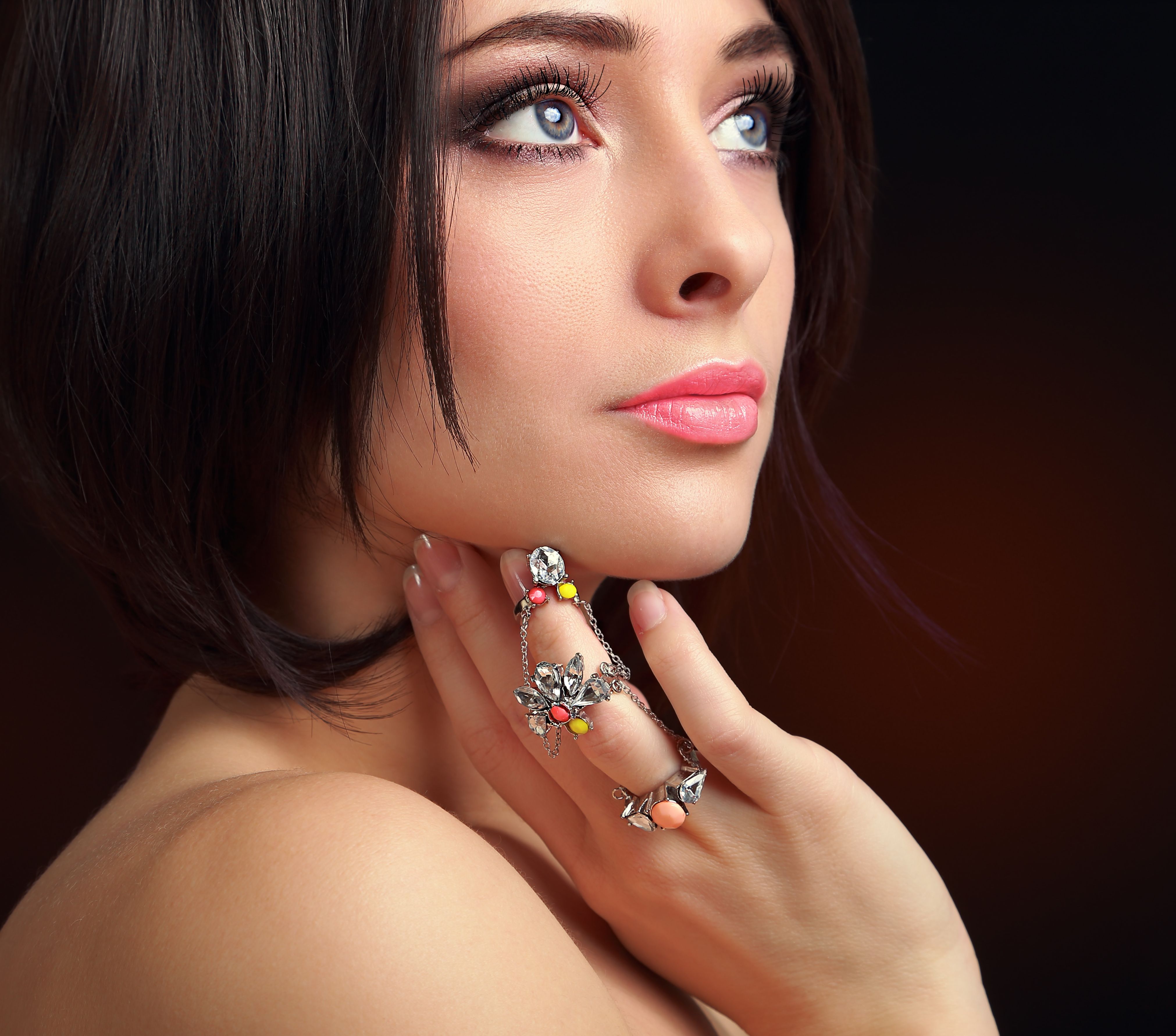 Beautiful makeup female face with ring on finger. Closeup portrait