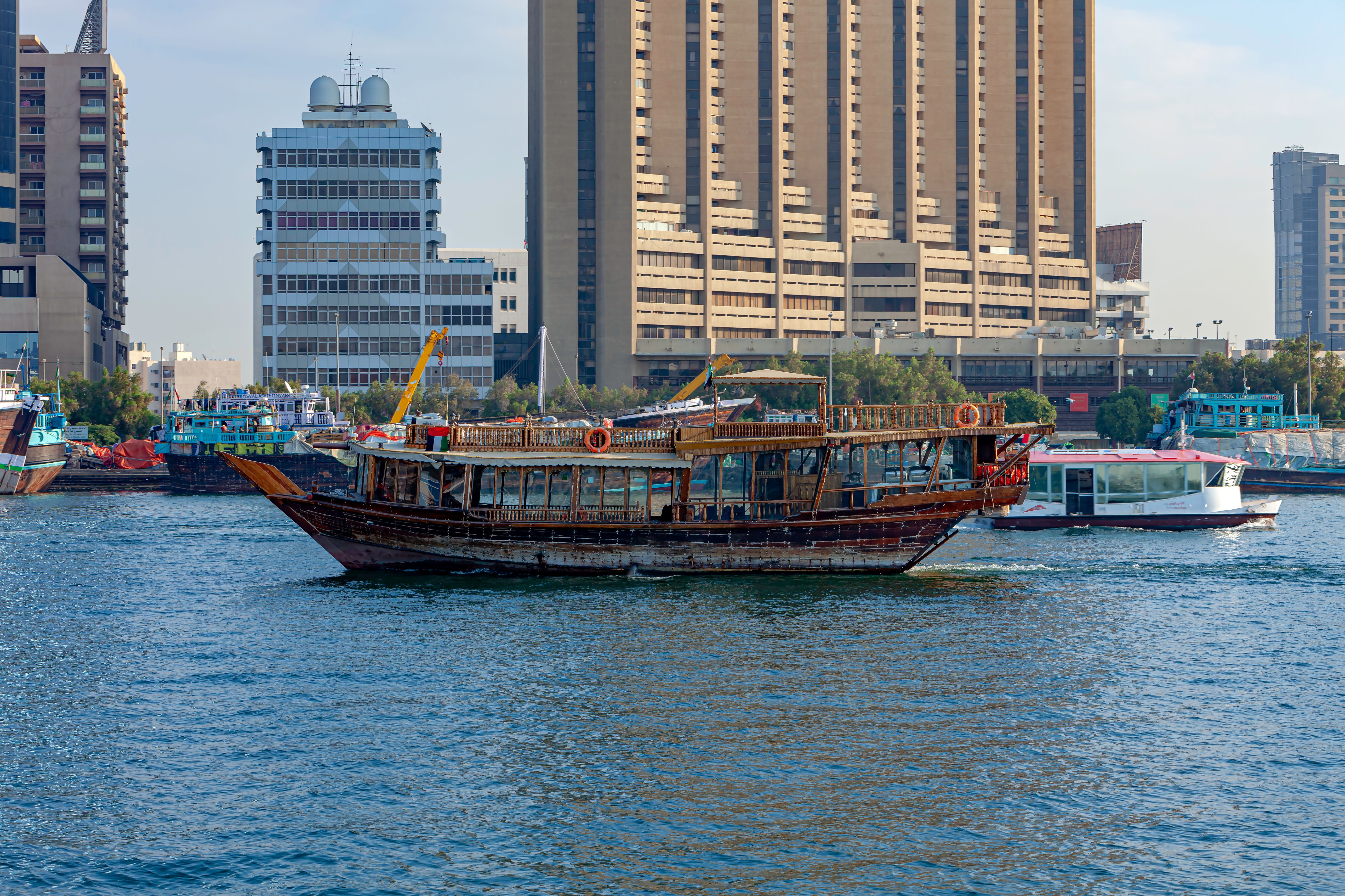 Dubai, United Arab Emirates - An Arab Dhow That Is Used For Lunch Or Dinner Cruises On Dubai Creek Is Seen Sailing By; It Is Currently Empty. Such Cruises Are Part Of Many Tourist Itineraries To The City. Background Deira Side Of The Creek.