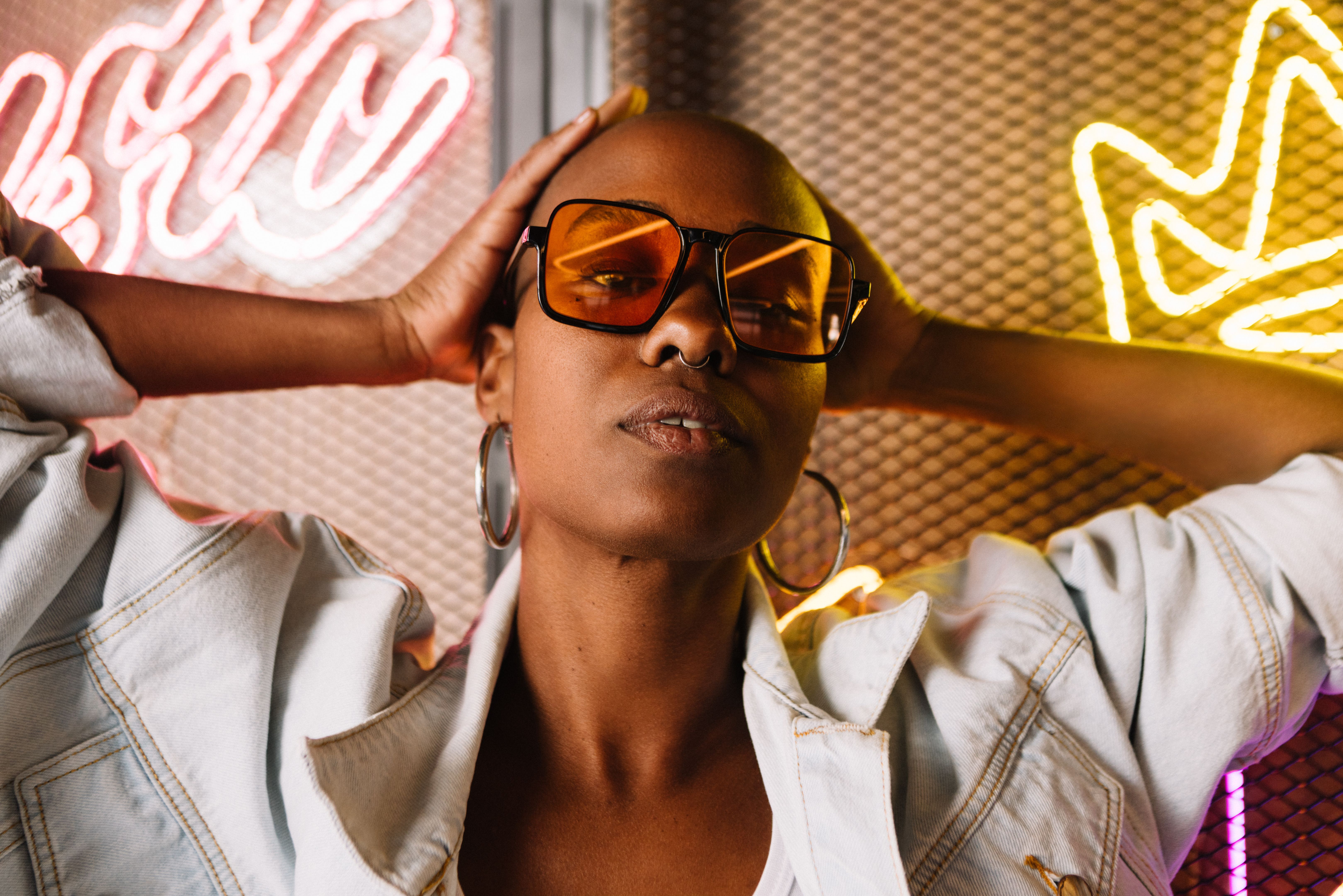 Stylish woman with sunglasses posing confidently in neon light studio Stylish woman with sunglasses posing confidently in neon light studio