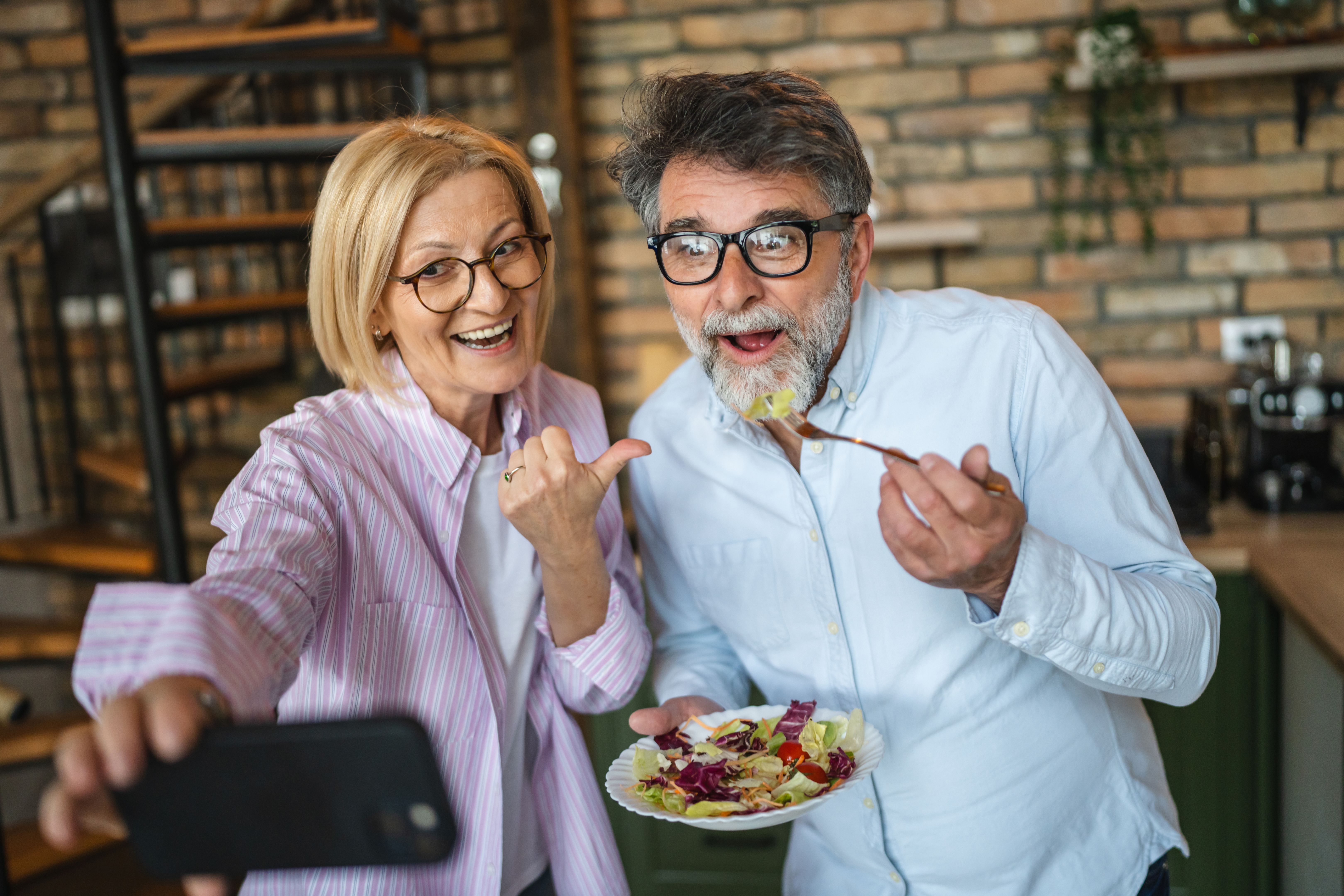 mature happy couple take a self portrait on cellphone with salad