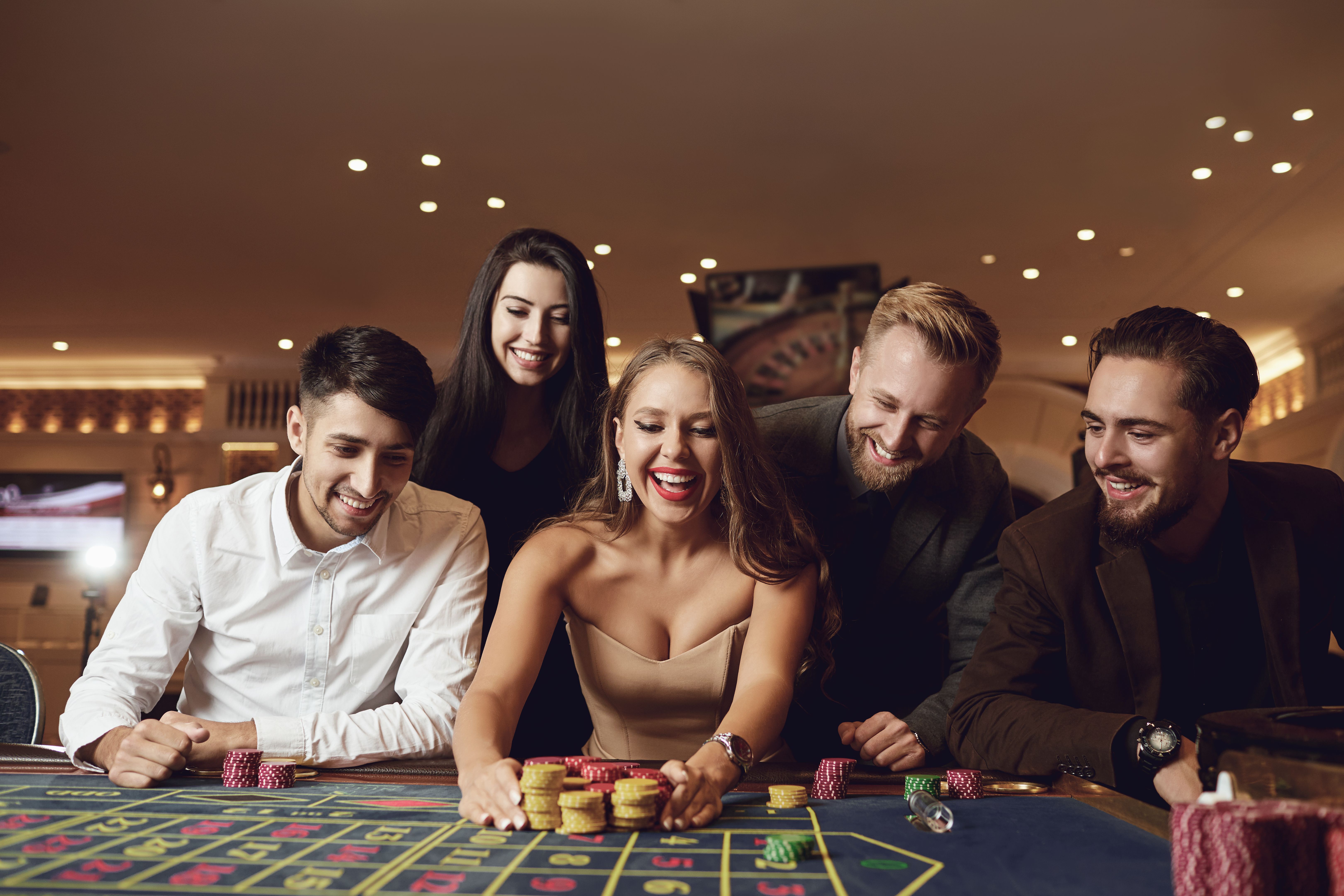 Happy people are betting in gambling at roulette poker in a casino Happy people are betting in gambling at roulette poker in a casino