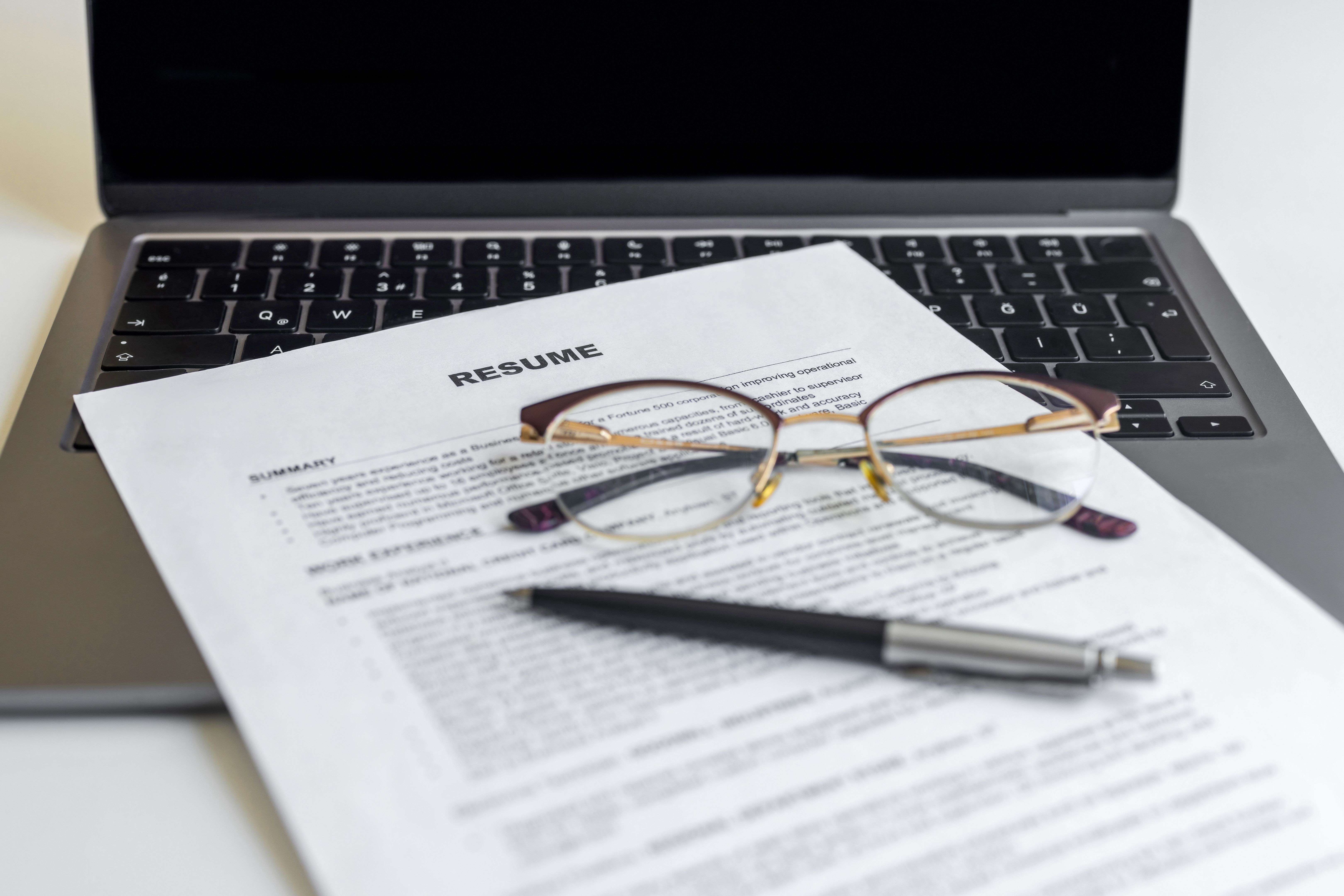 Resume paper and glasses on laptop