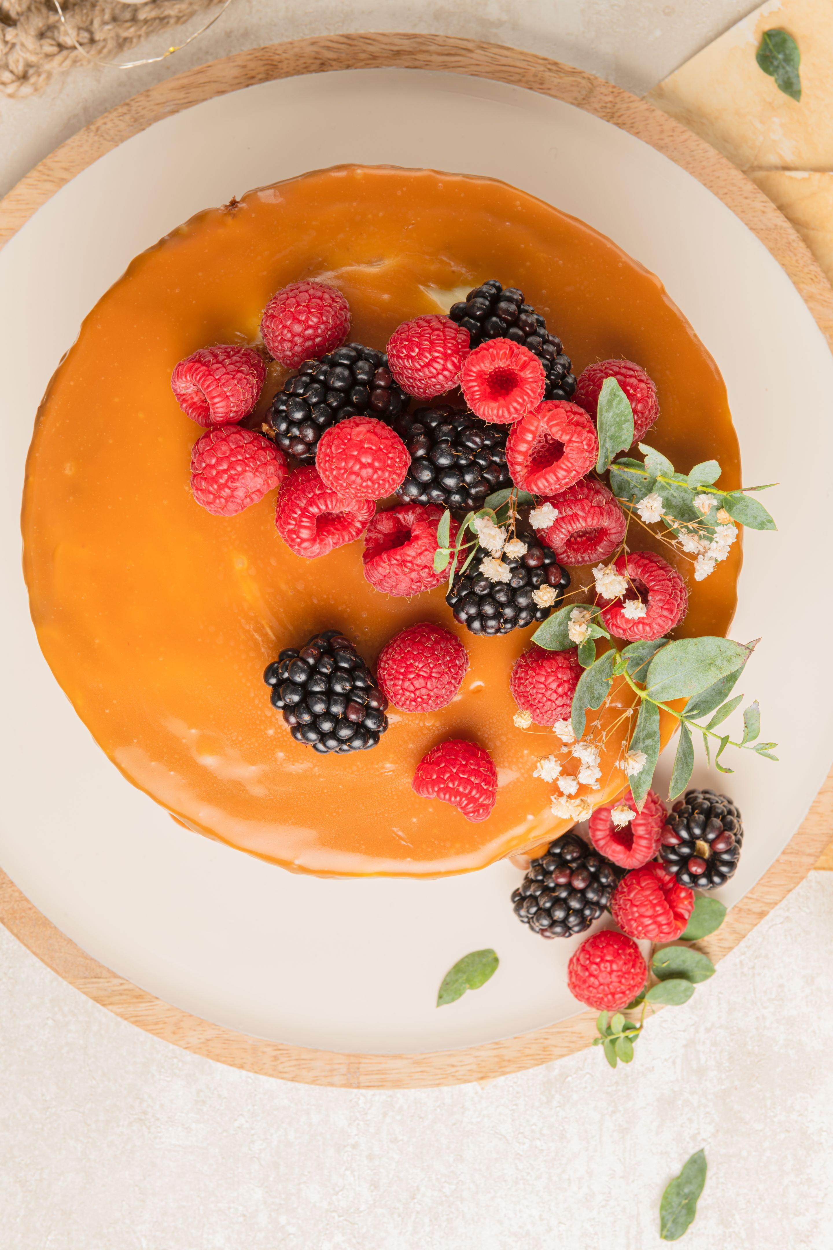 Delicious chocolate cake topped with mascarpone cream and salted caramel. Decorated with red fruits. Light background