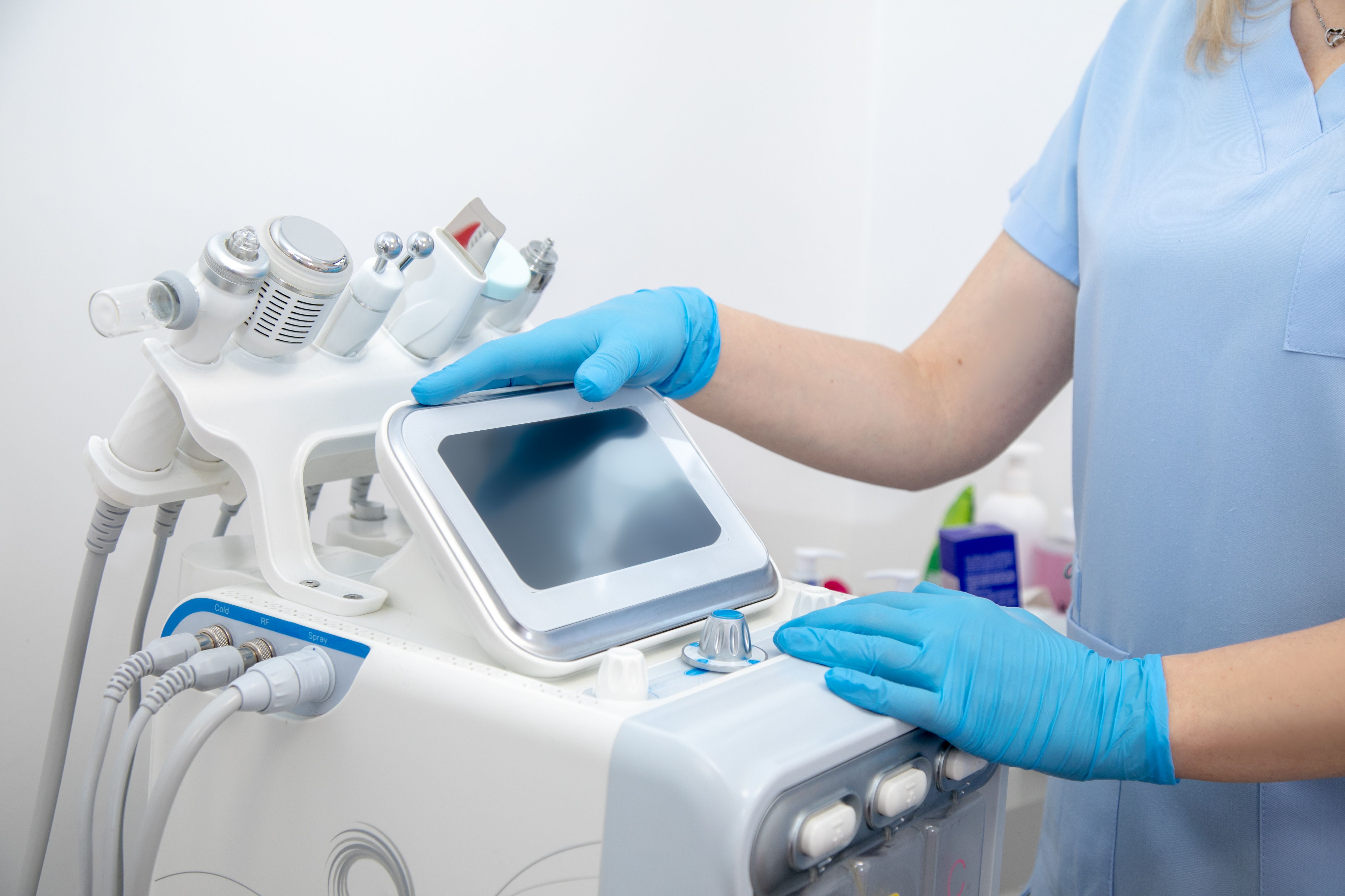 Cropped professional dermatologist setting up and using Hydradermabrasian peel machine with hand pieces cables. Electrolysis