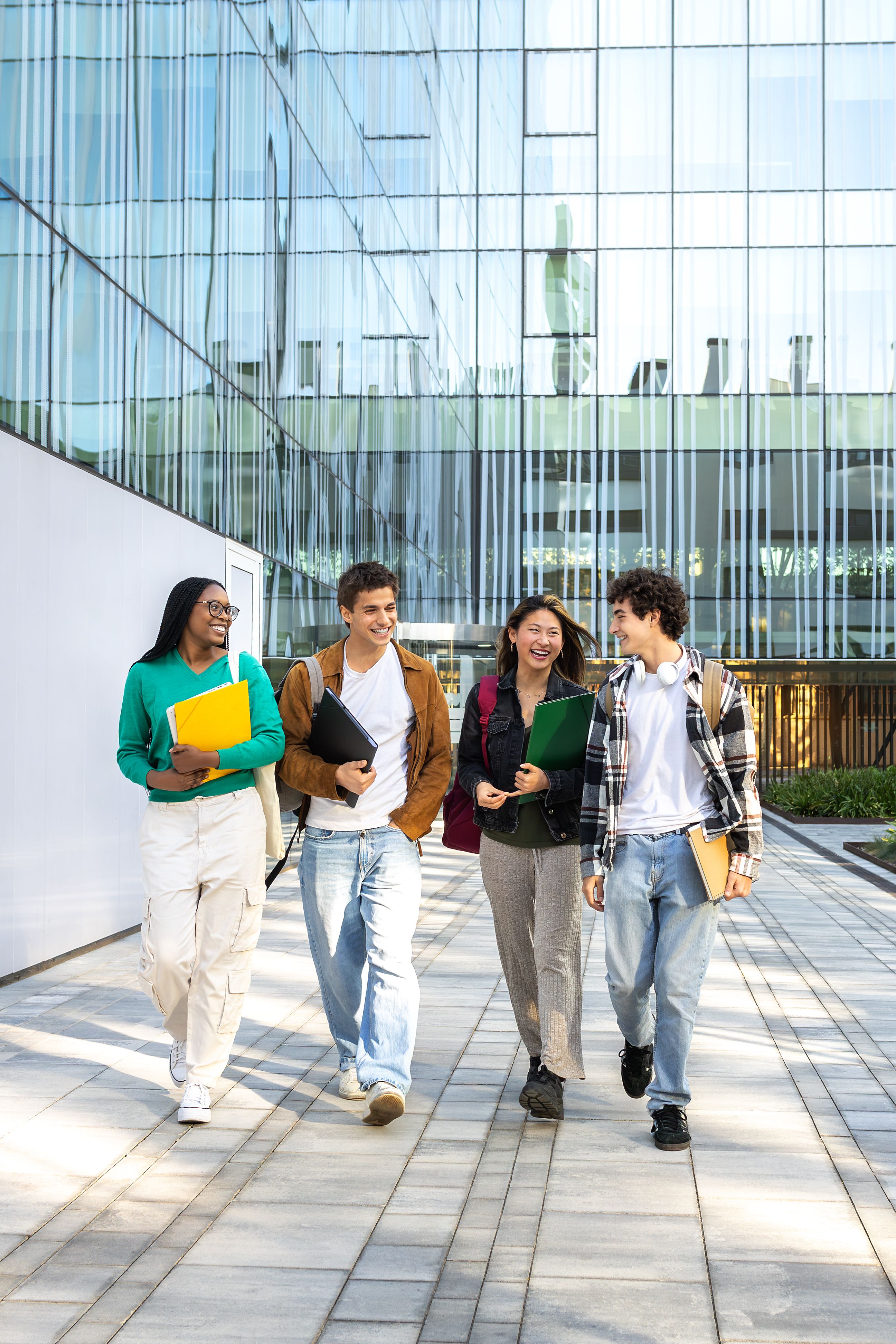 Vertical image of multiracial happy university students walking to class together laughing and talking. Vertical image of multiracial happy university students walking to class together laughing and talking.