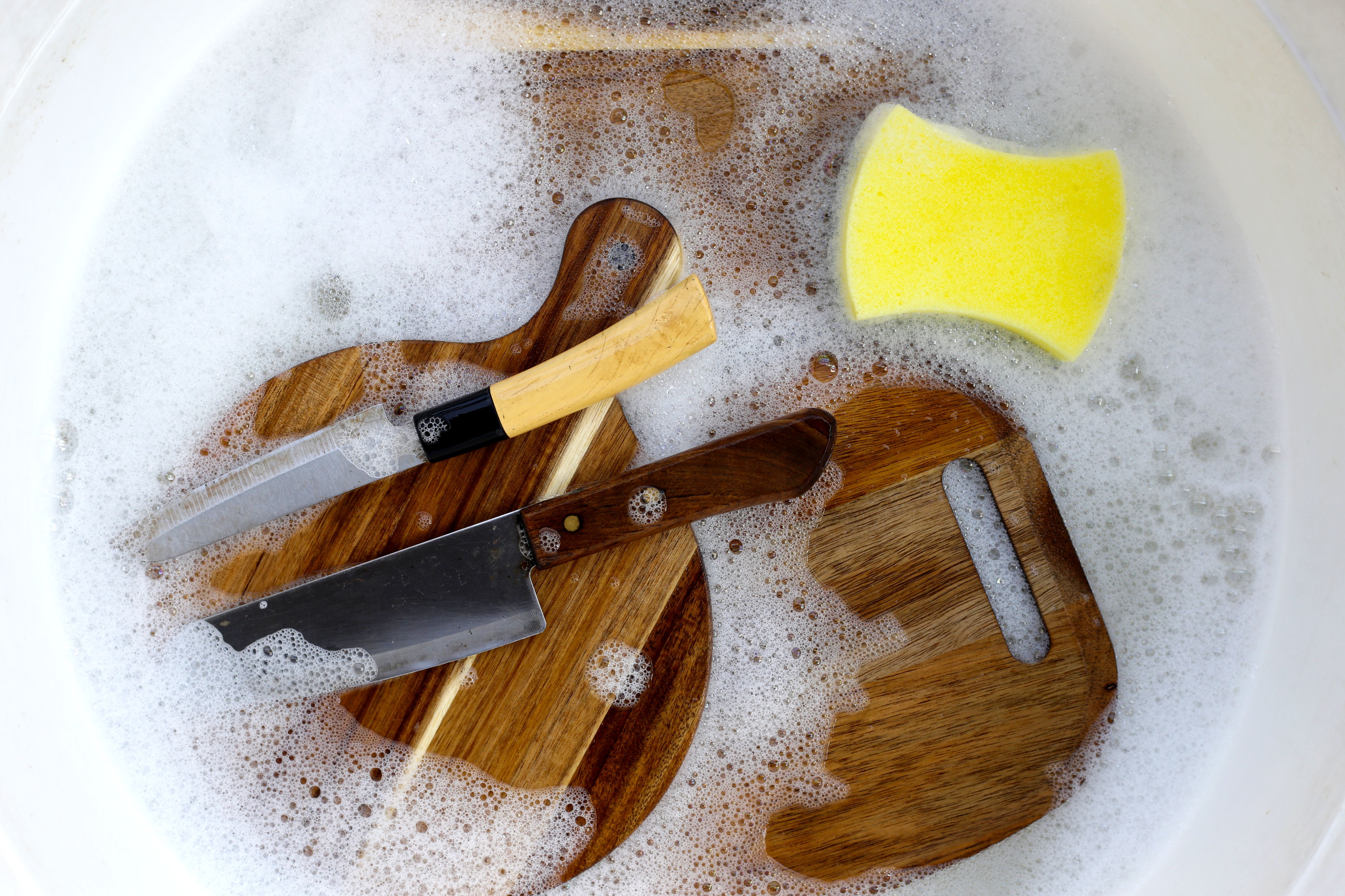 Wooden cutting board in foam of dishwashing liquid.