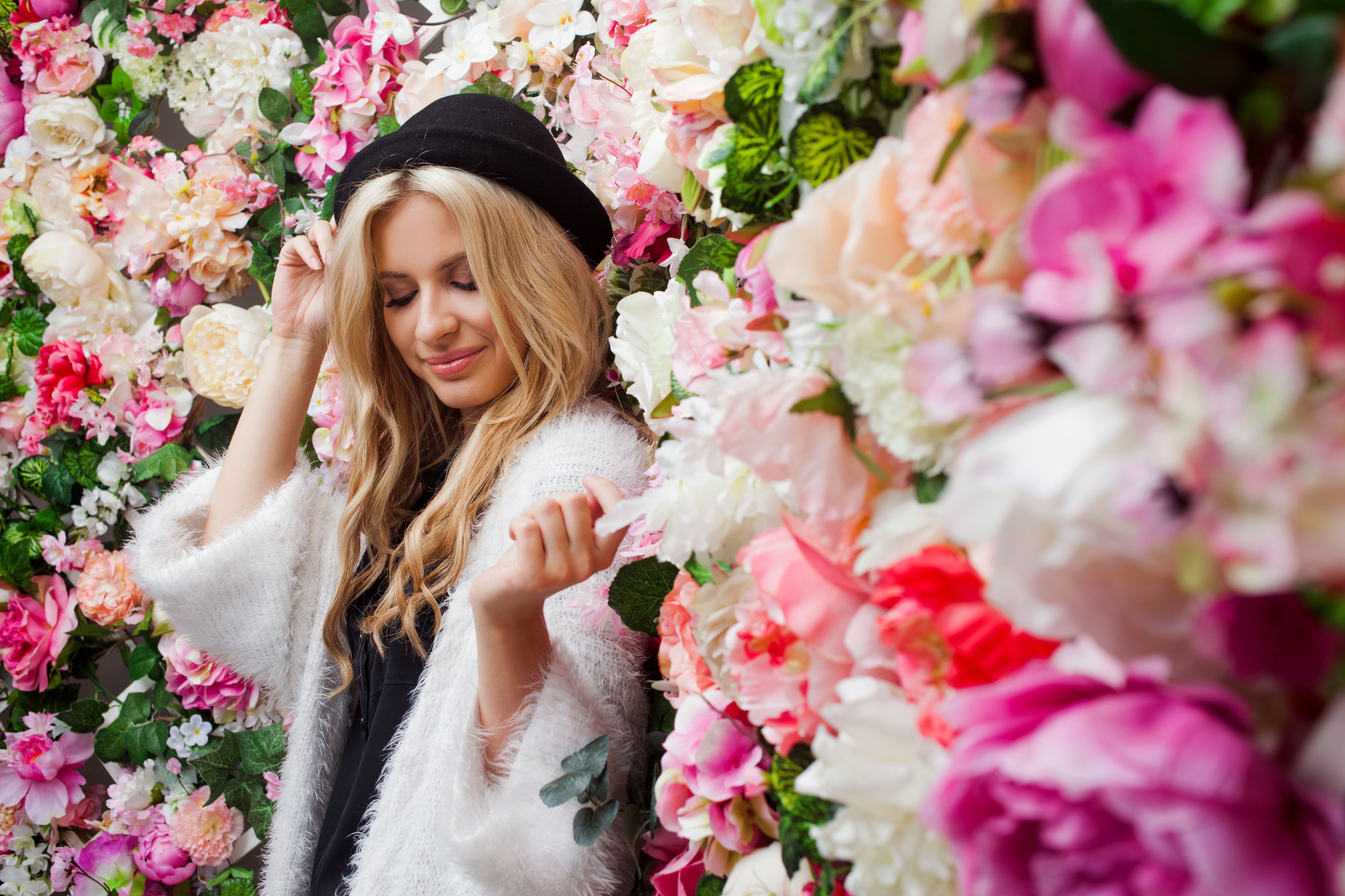 Young beautiful blonde woman in fashionable hat on floral background