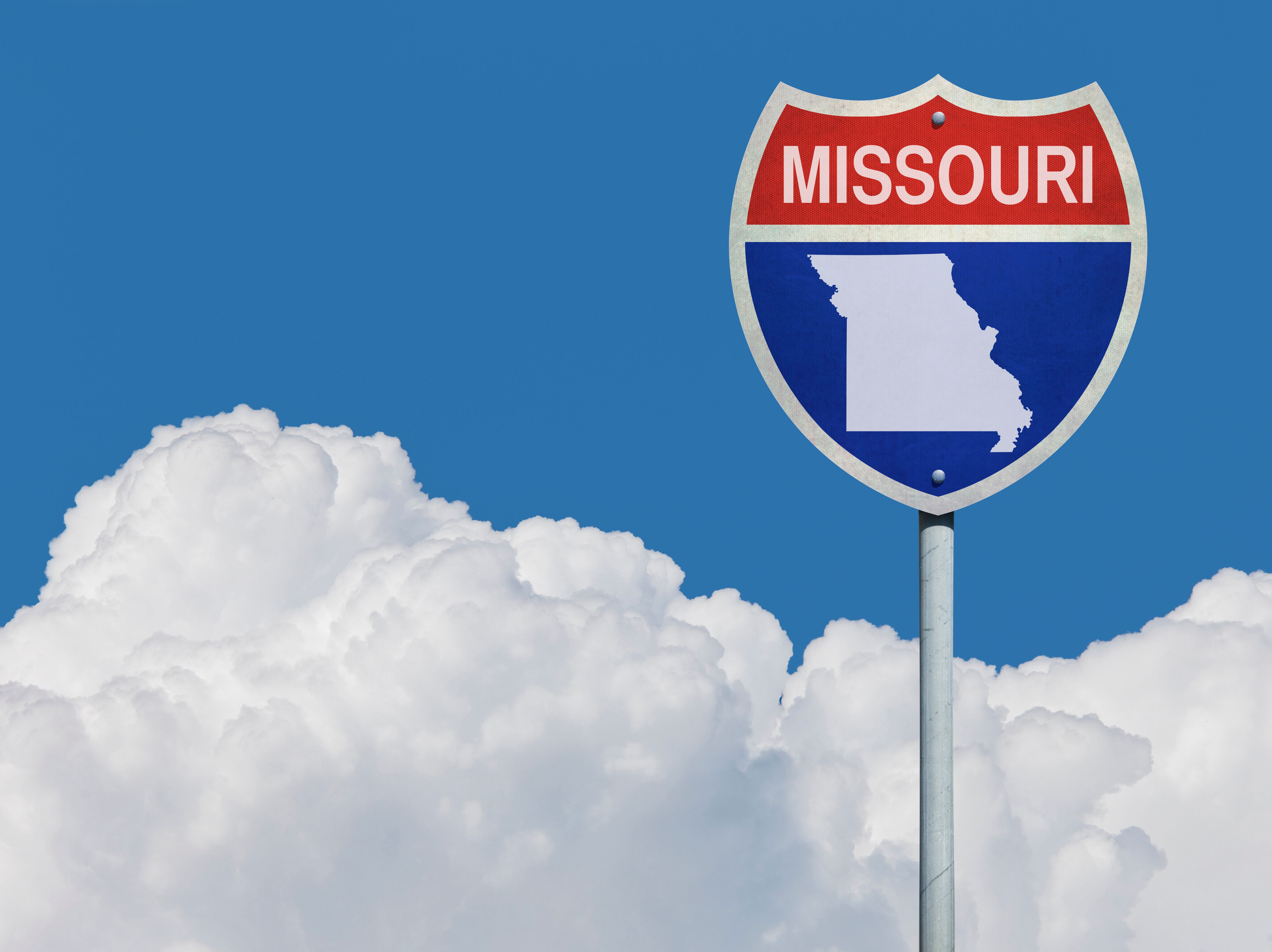 Highway sign for Interstate road in Missouri with map in front of clouds