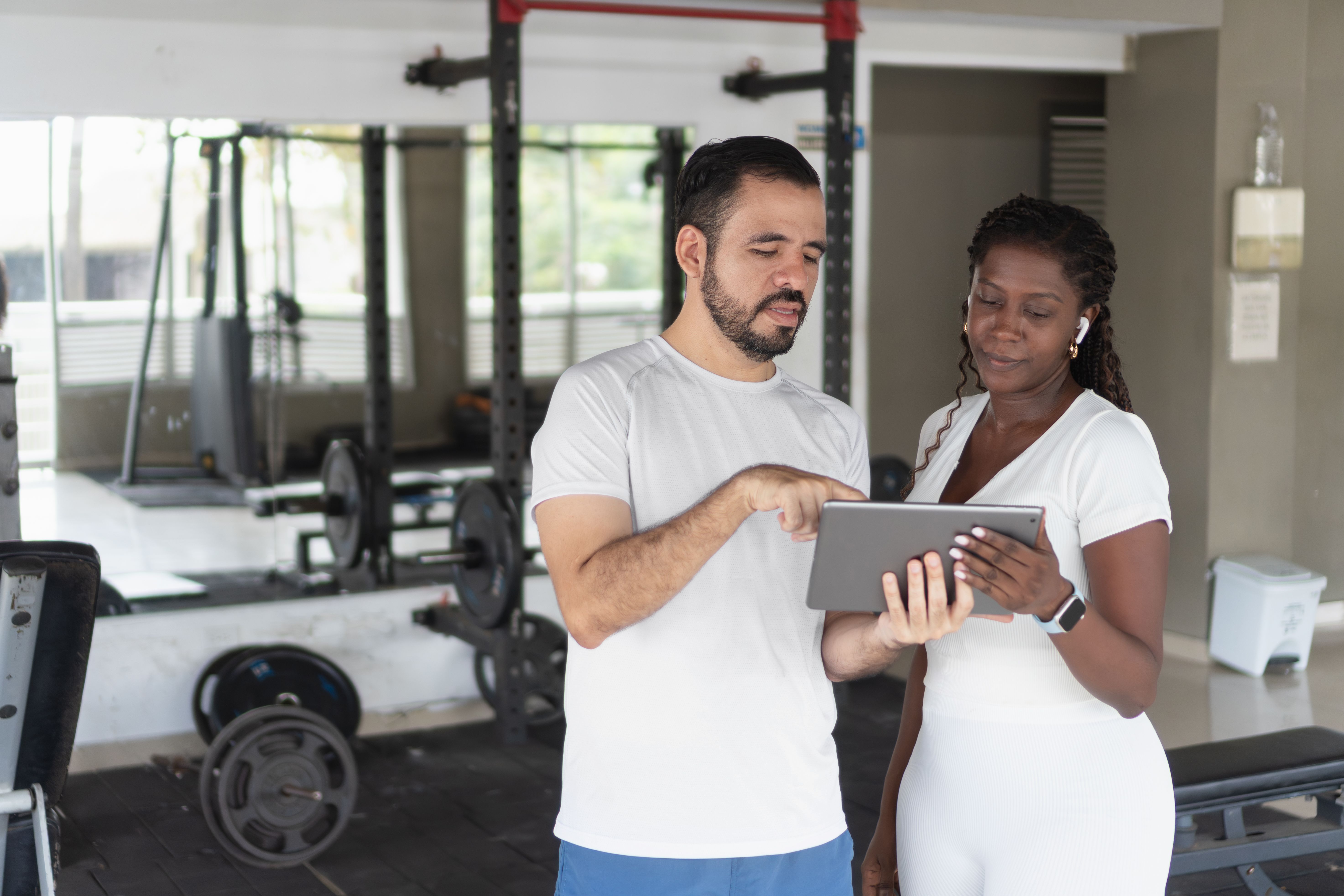 Personal trainer showing something on tablet to client at gym