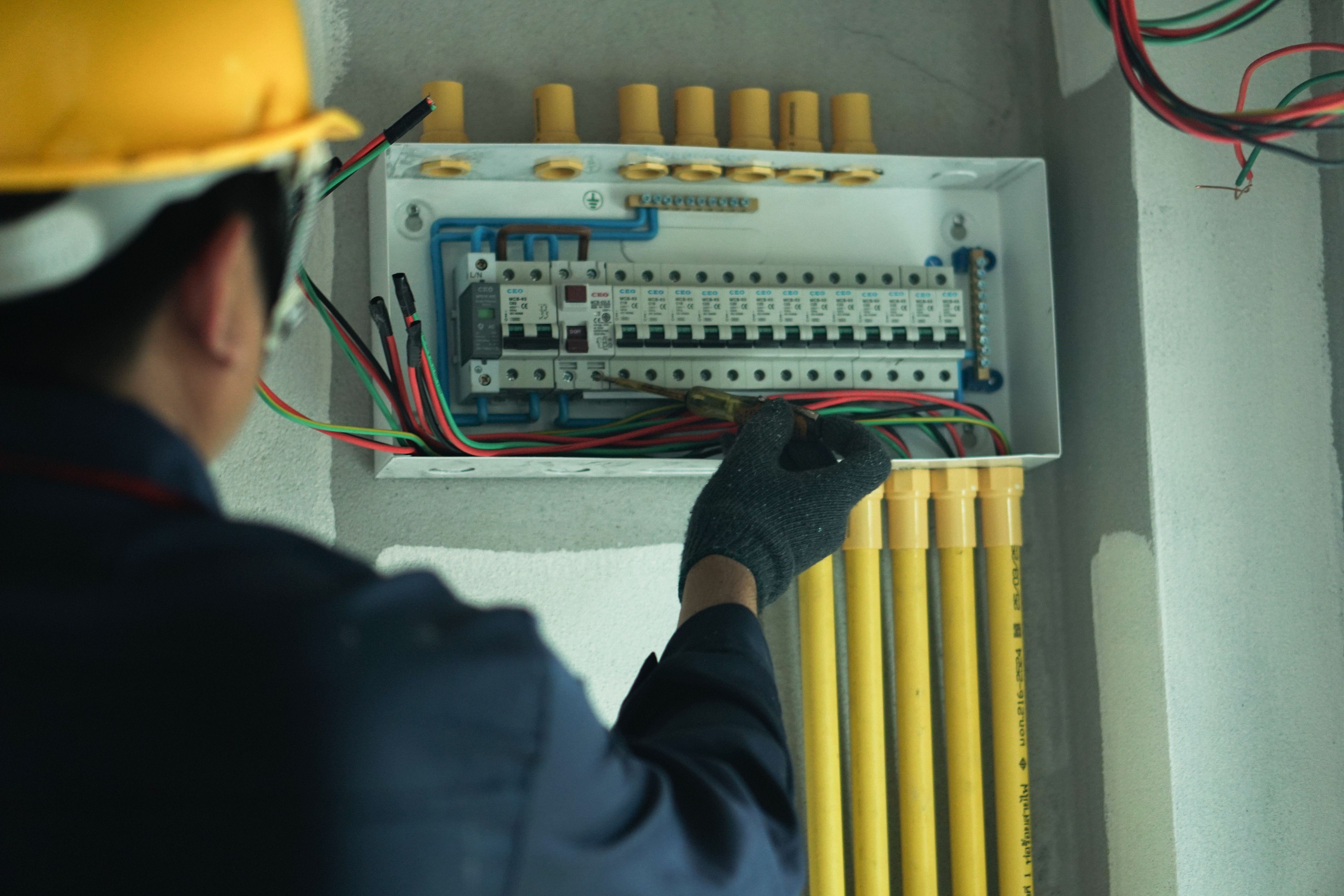 An electrician is using a device to check the electrical current for electrical installation in a home. An electrician is using a device to check the electrical current for electrical installation in a home.
