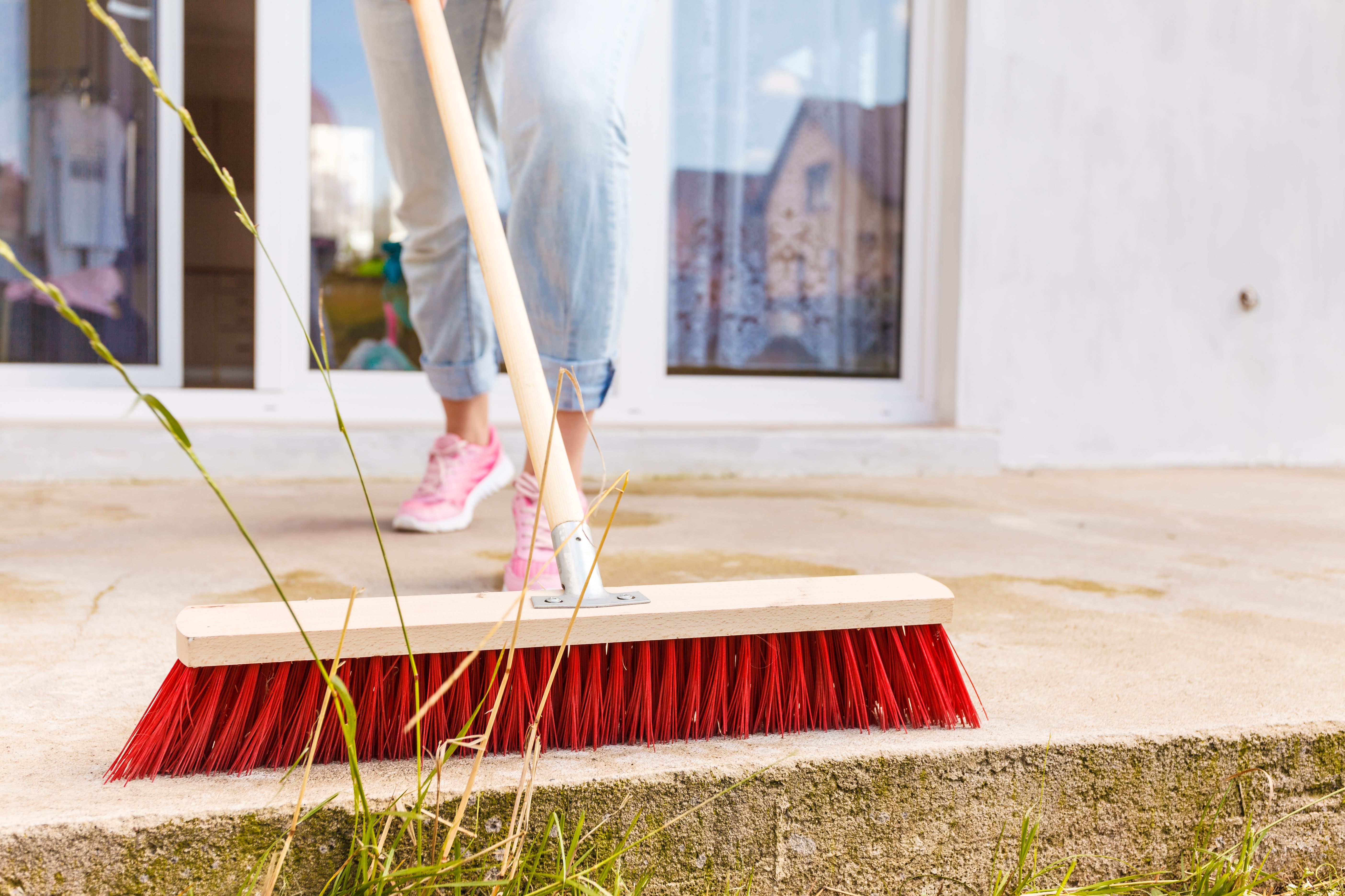Person cleaning patio using brush broom