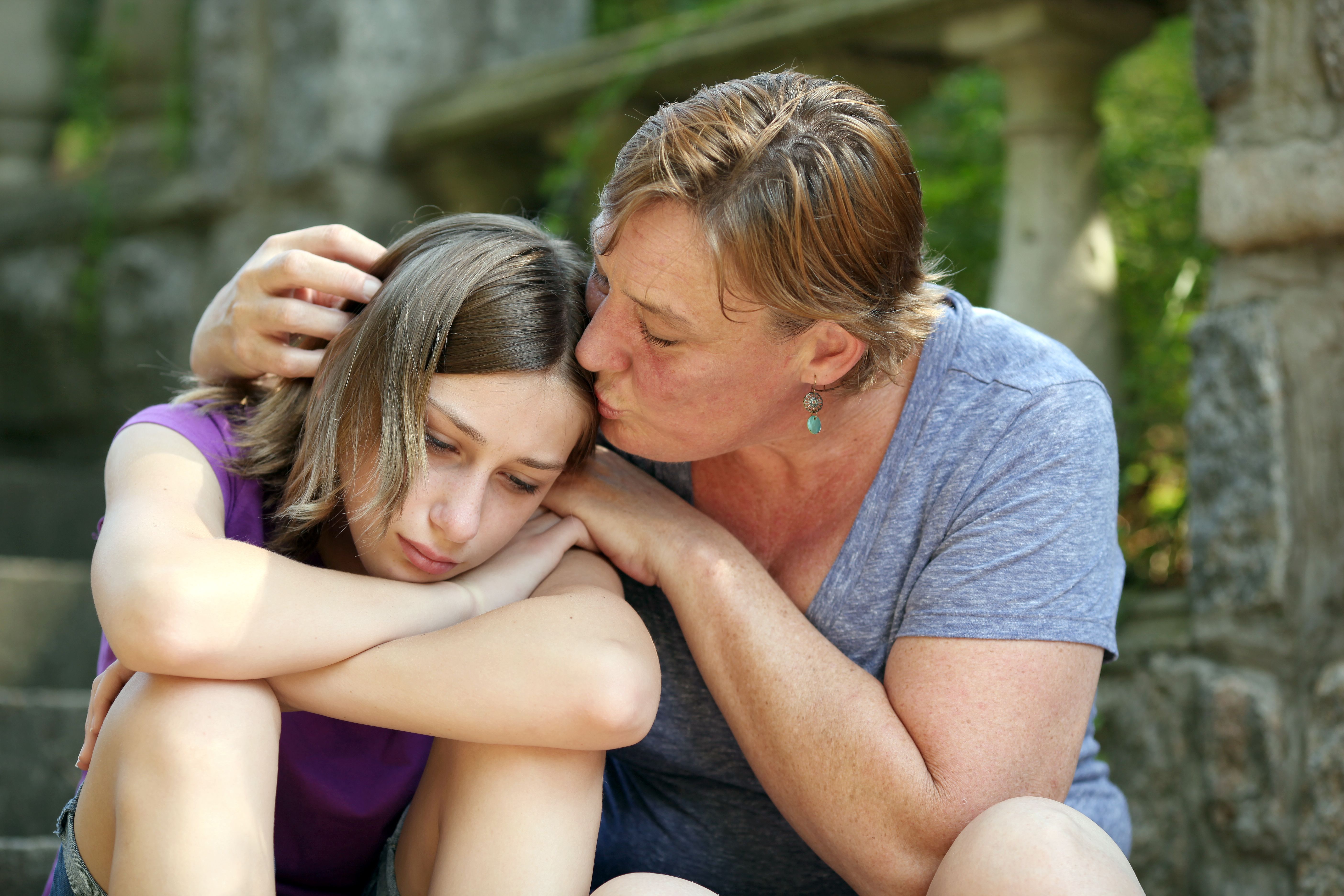 Mother consoles daughter with a kiss.