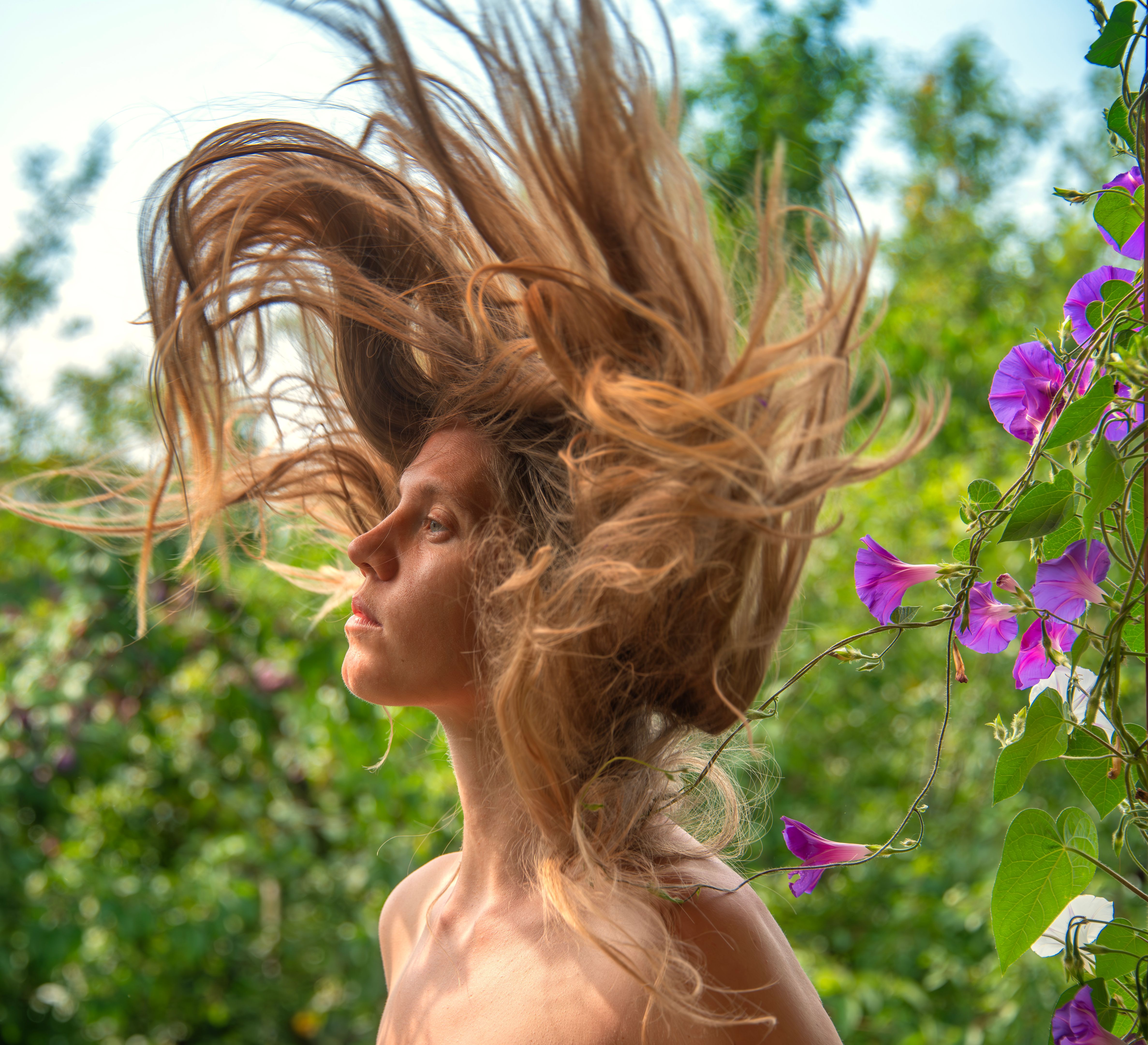 Portrait of young woman in lush foliage with flowers in nature