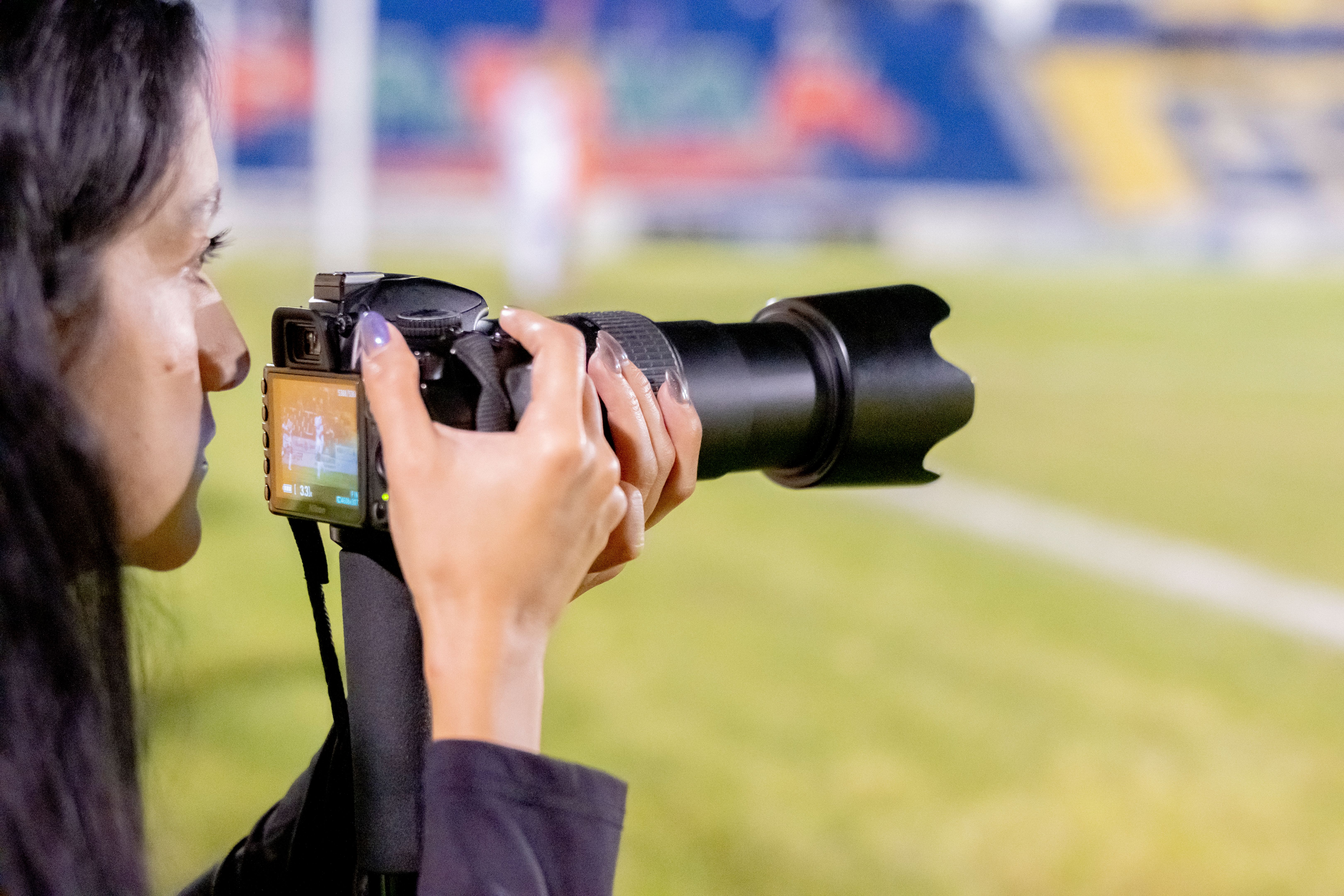 Photojournalist working at a soccer event on the field with the stadium in the background