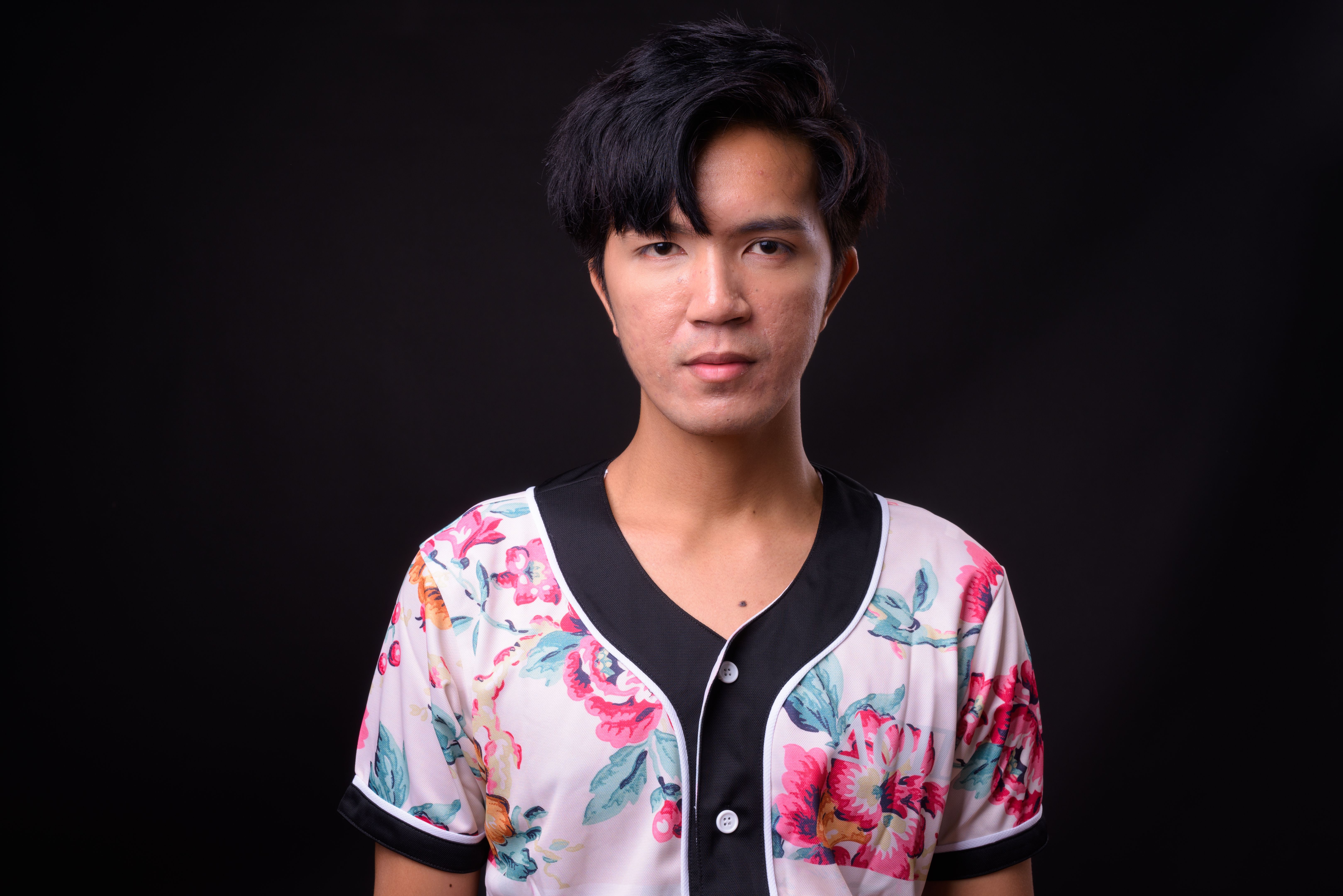 Young handsome Asian man against black background