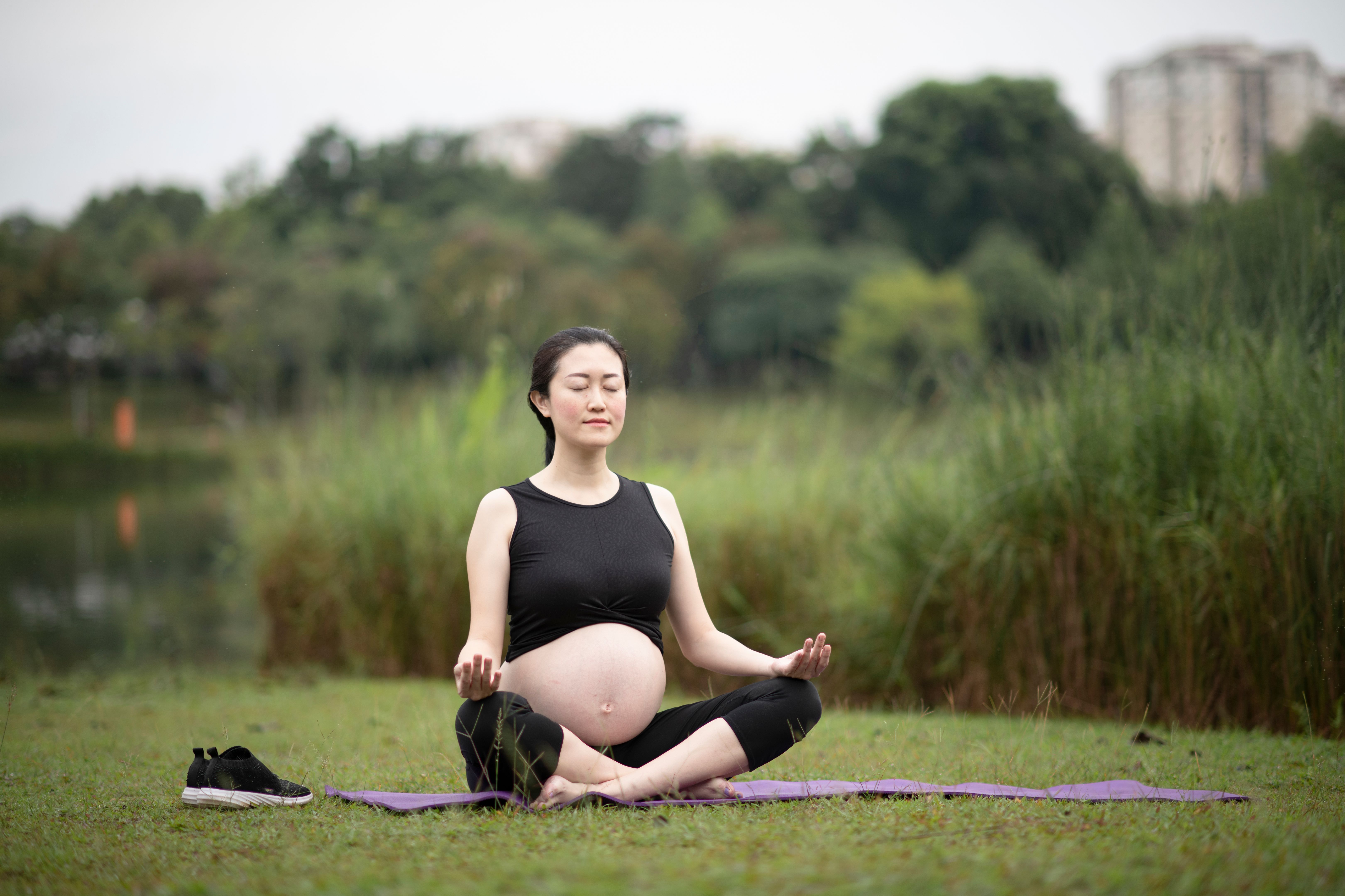 asian chinese pregnant woman practicing yoga at public park