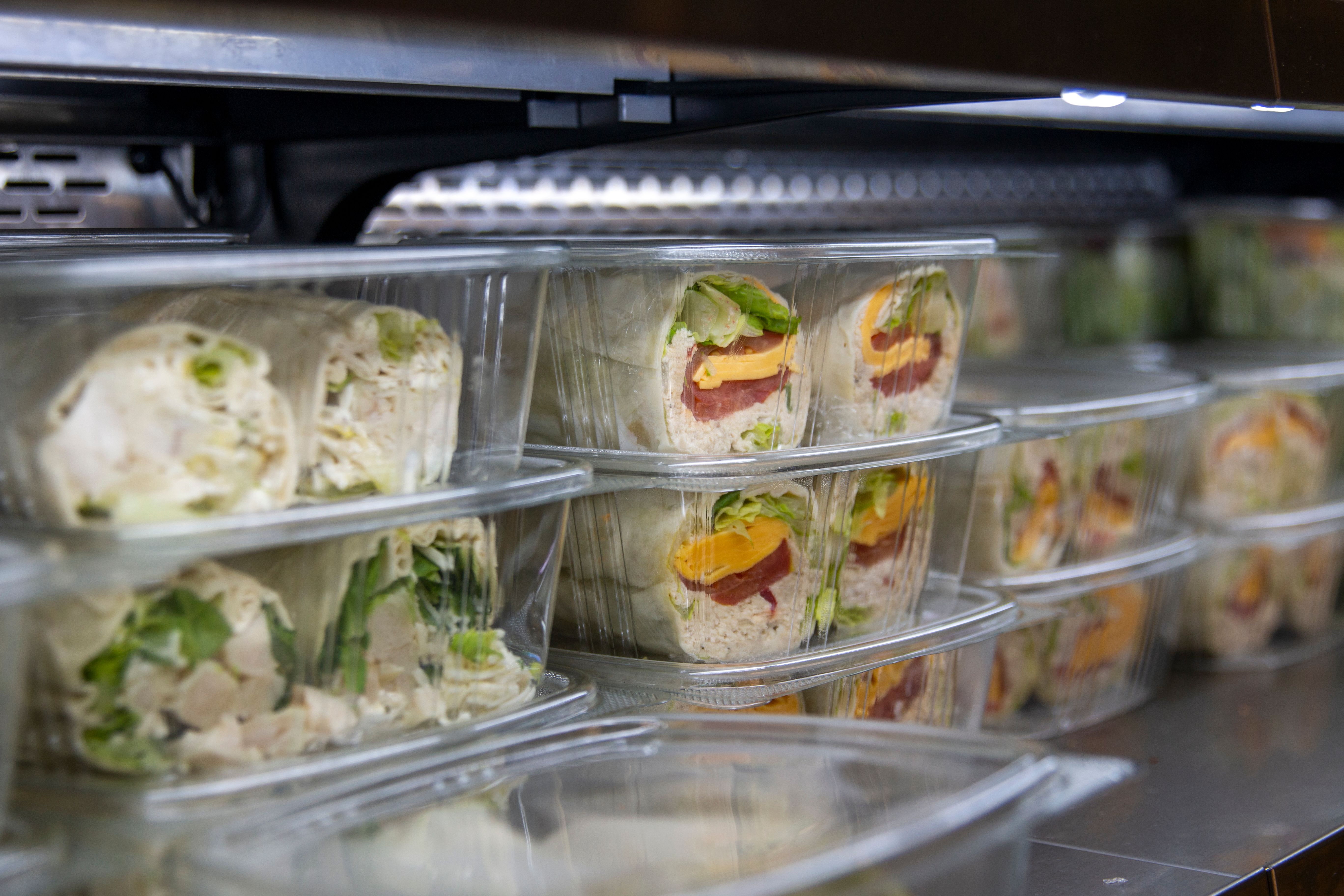 Freshly prepared wraps stored neatly in containers at a deli, showcasing a variety of ingredients and colors for healthy eating Freshly prepared wraps stored neatly in containers at a deli, showcasing a variety of ingredients and colors for healthy eating