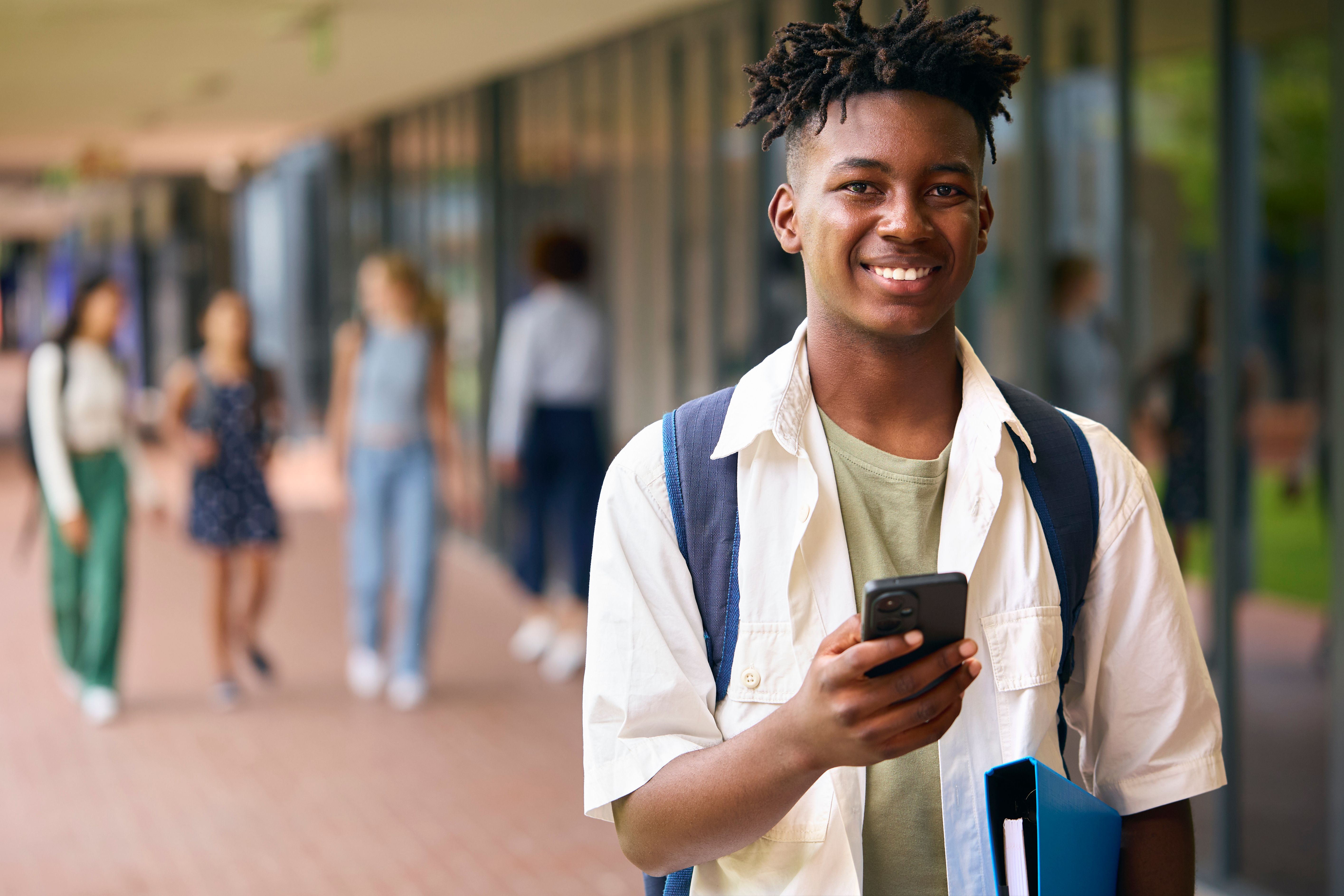 Portrait Of Male Secondary Or High School Student Outdoors At School With Mobile Phone Portrait Of Male Secondary Or High School Student Outdoors At School With Mobile Phone