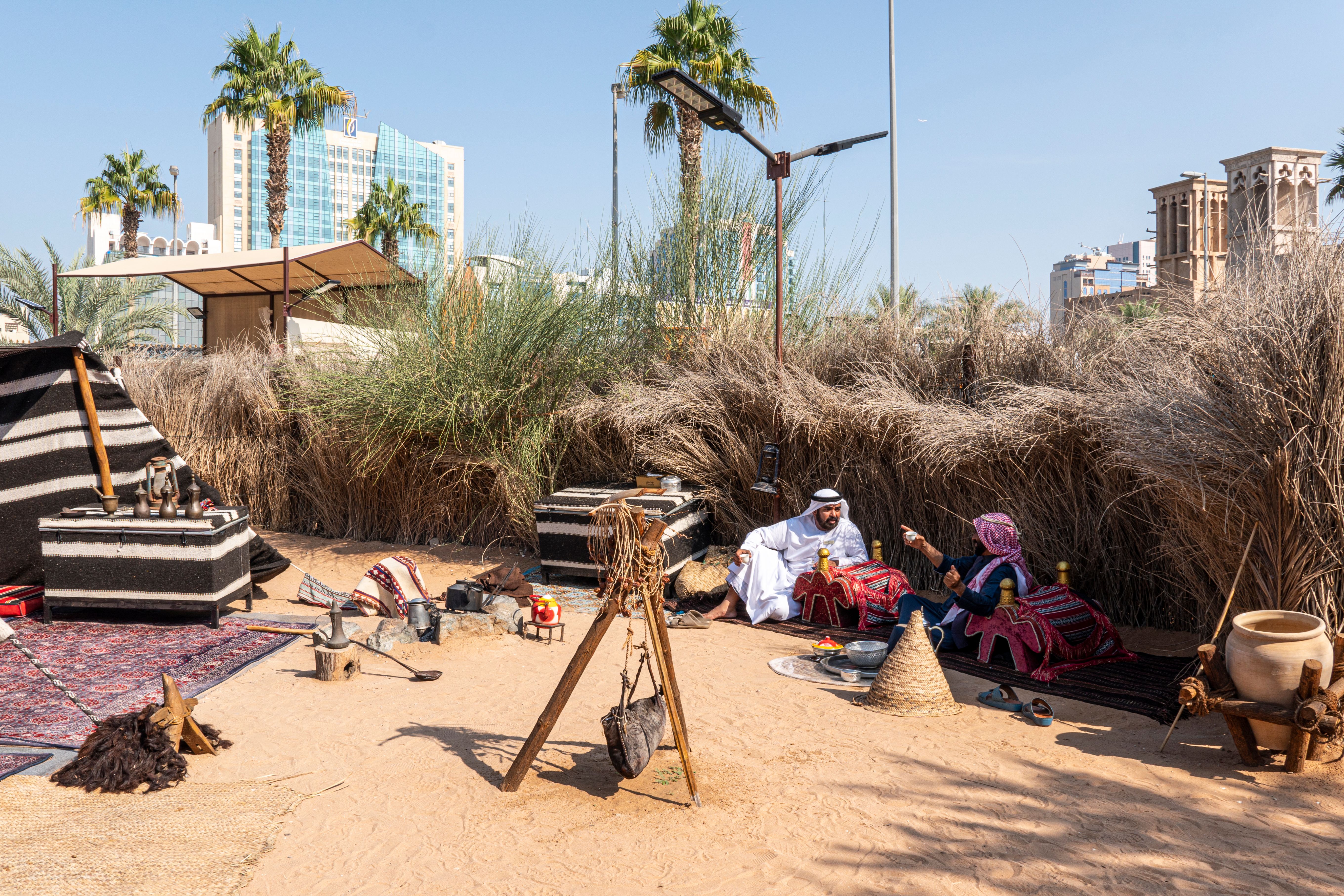 two Arabs are sitting near a campfire drinking coffee and they talk. Dubai, United Arab Emirates. Dubai