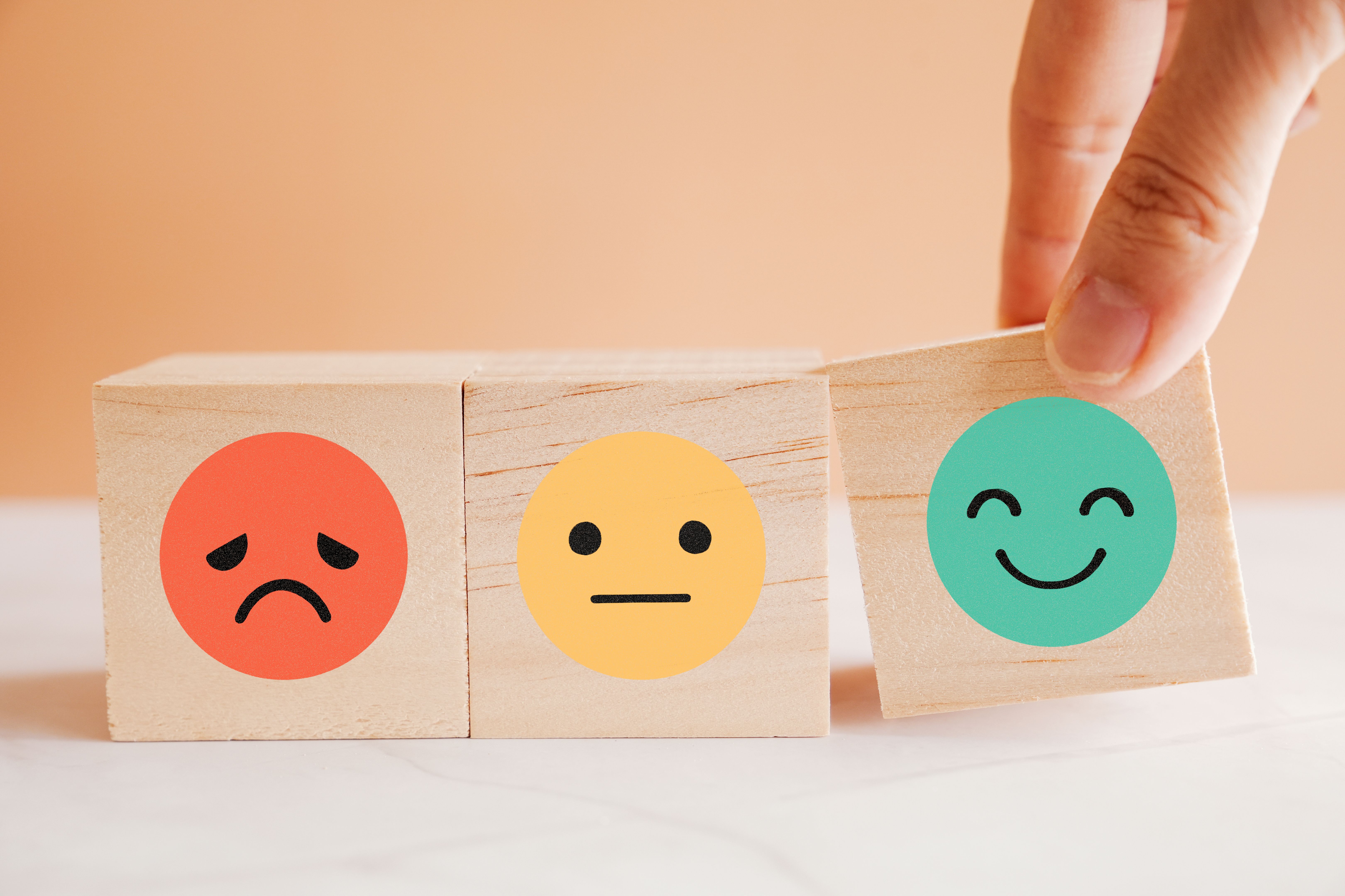 Hand choosing happy smile face wooden block, good feedback rating and positive customer review, mental health assessment, child wellness,world mental health day, think positive, compliment day concept