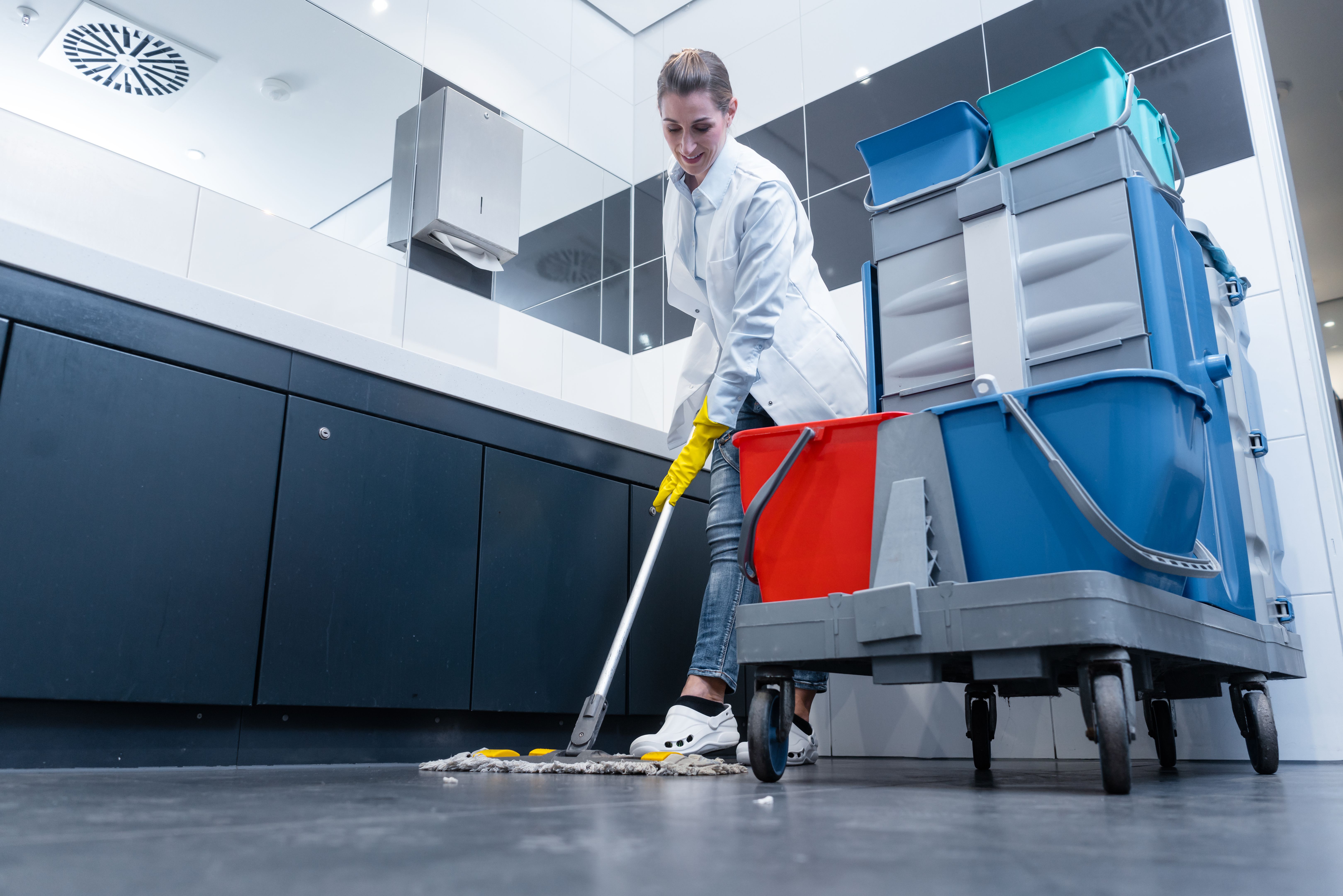 Femme de ménage la serpillière dans les toilettes