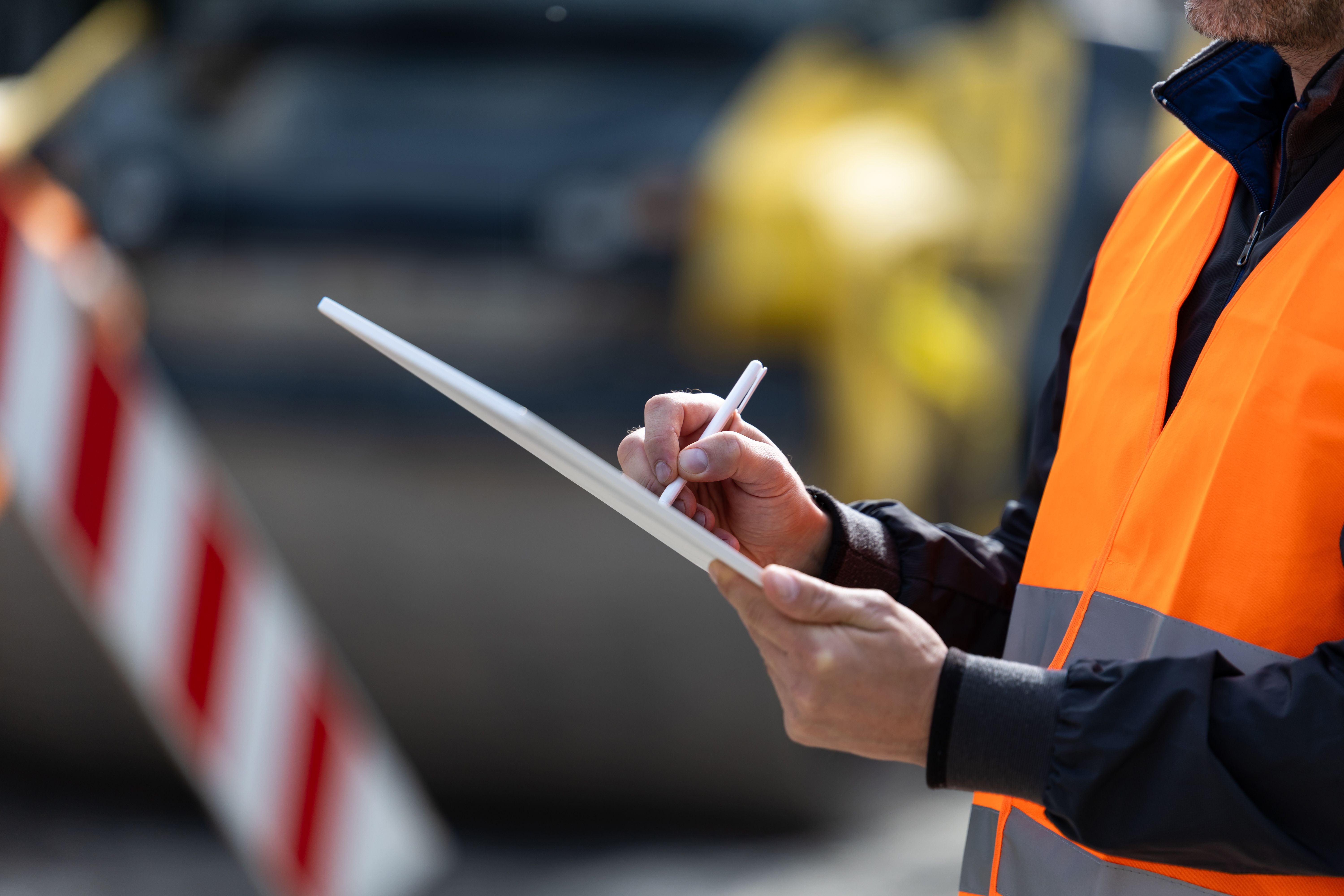 Fire alarm worker taking notes while monitoring site activities at a property area during daylight