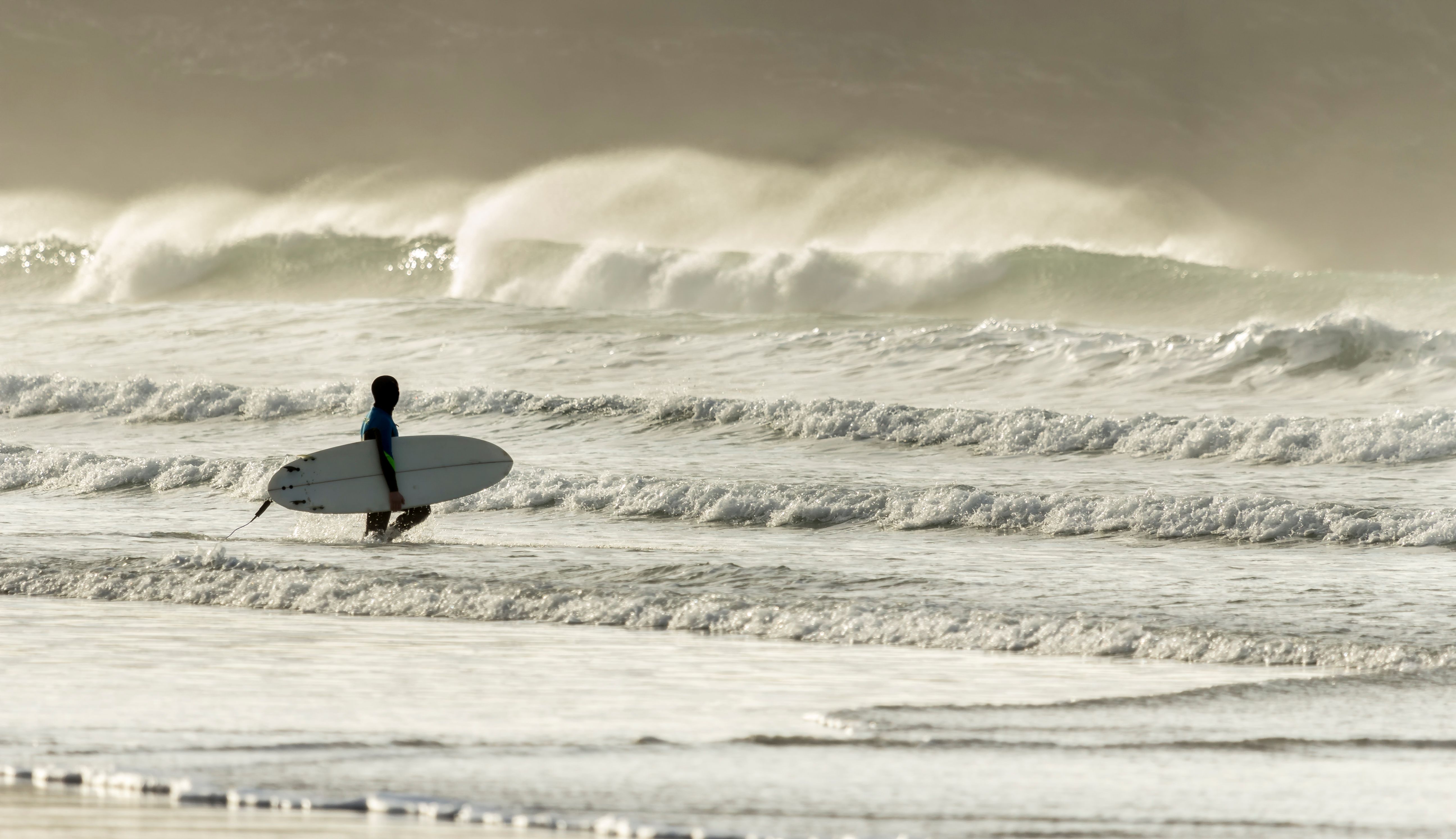 Surfer approaches Waves, Fistral Beach, Cornwall, UK
