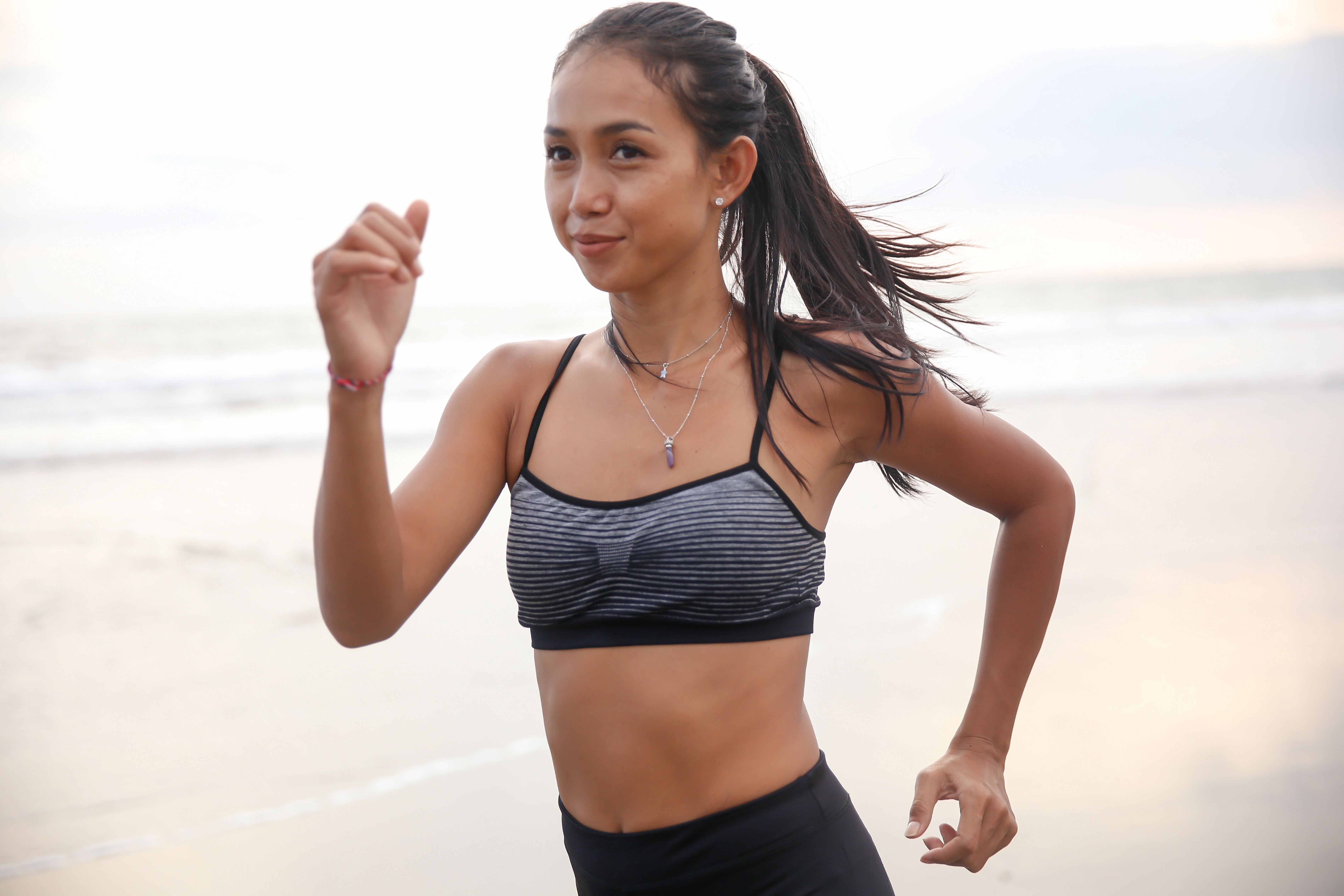 Smiling Indonesian woman running fast on the beach