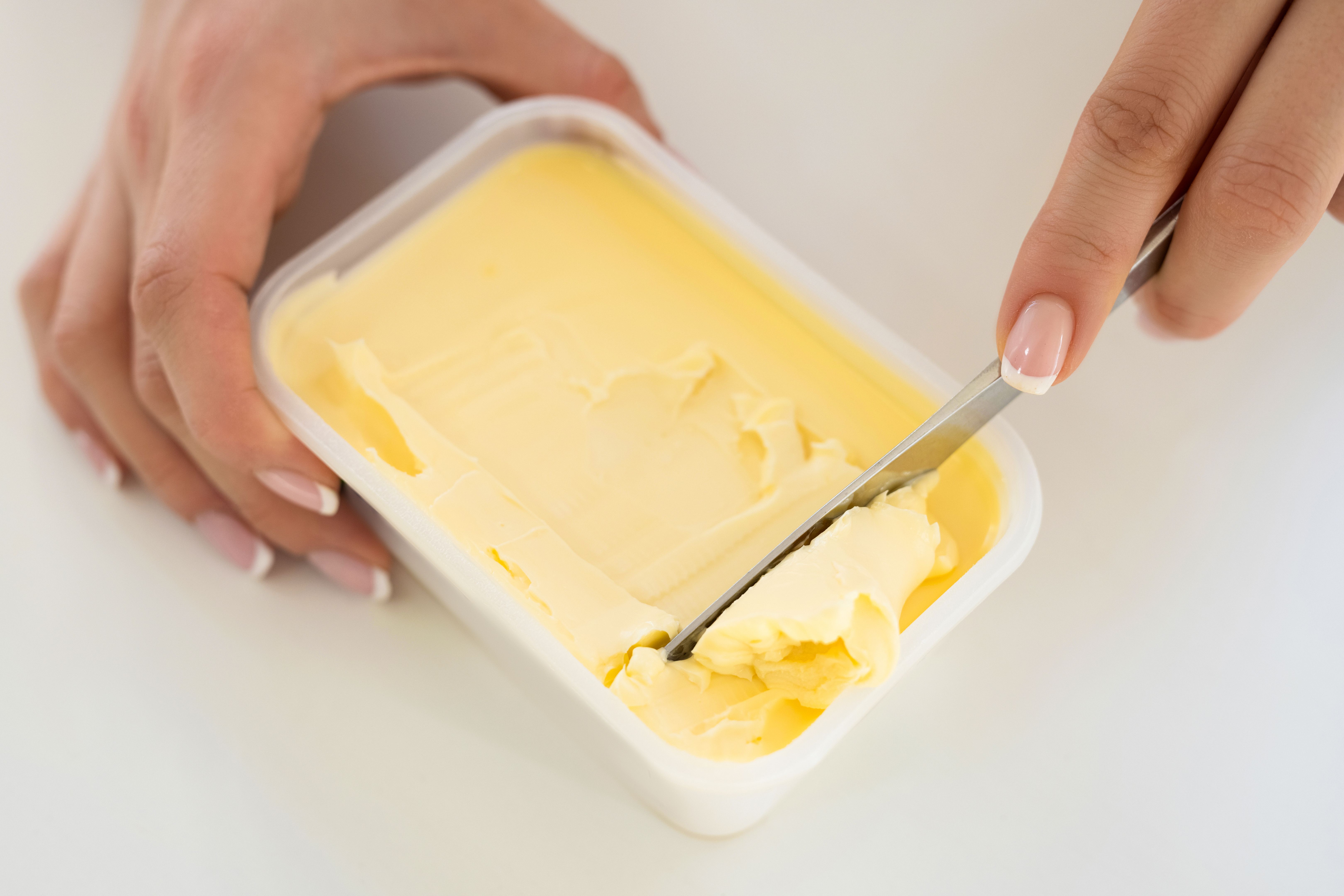 Butter in plastic container with knife