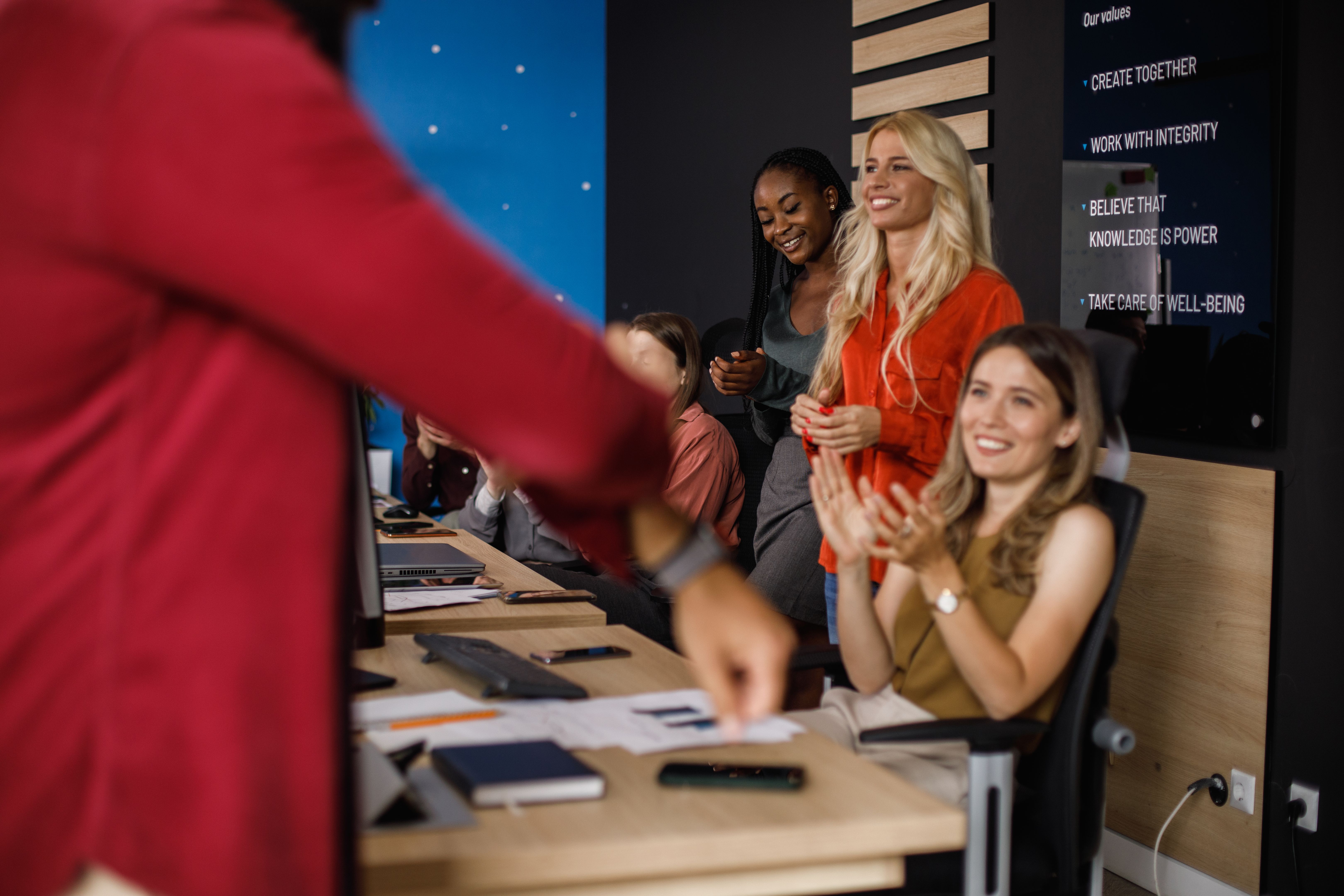 Businessman rolling up his sleeve, his coworkers applauding him at the beginning of a meeting