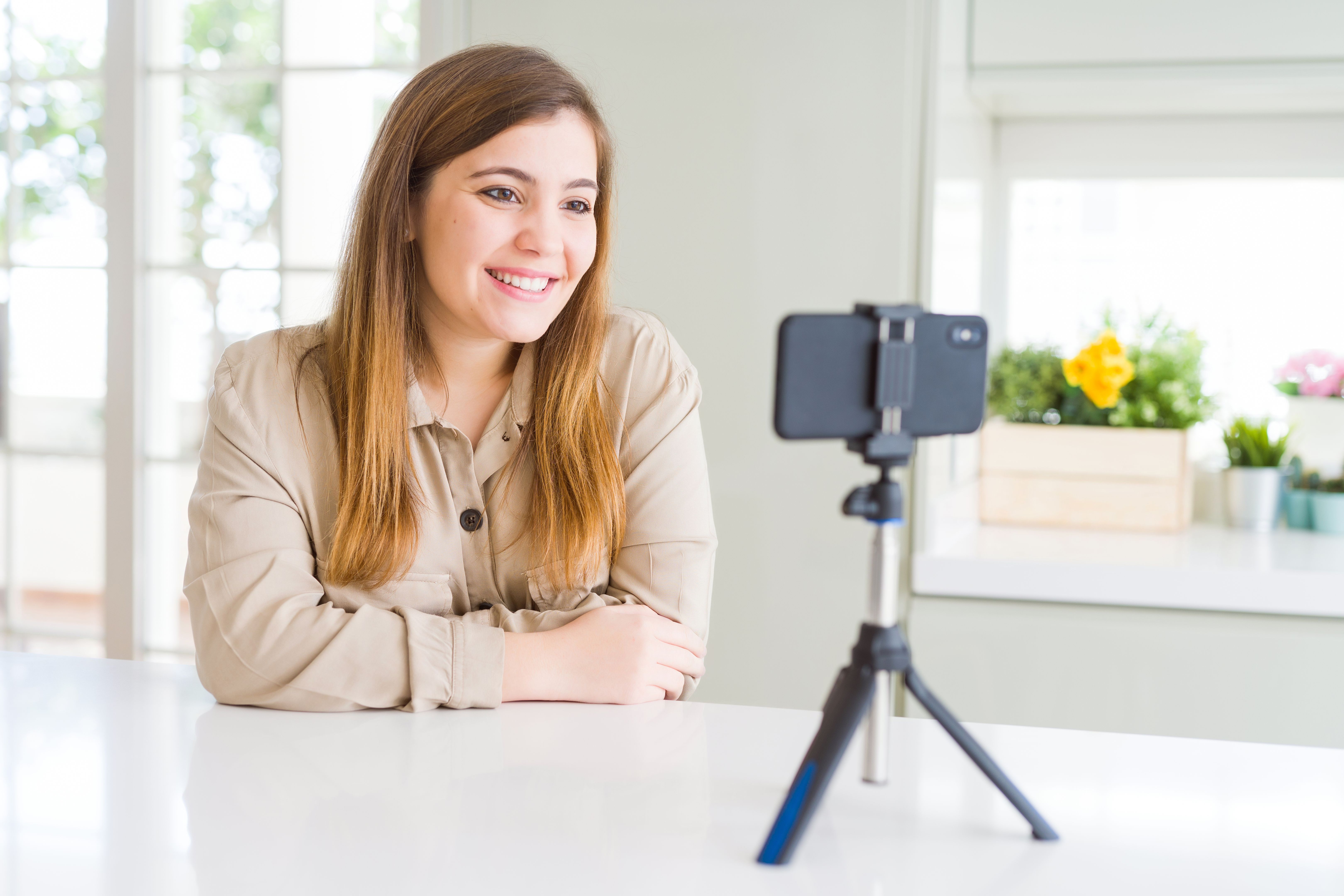 Beautiful young woman doing online video call using smartphone webcam happy face smiling with crossed arms looking at the camera. Positive person. Beautiful young woman doing online video call using smartphone webcam happy face smiling with crossed arms looking at the camera. Positive person.