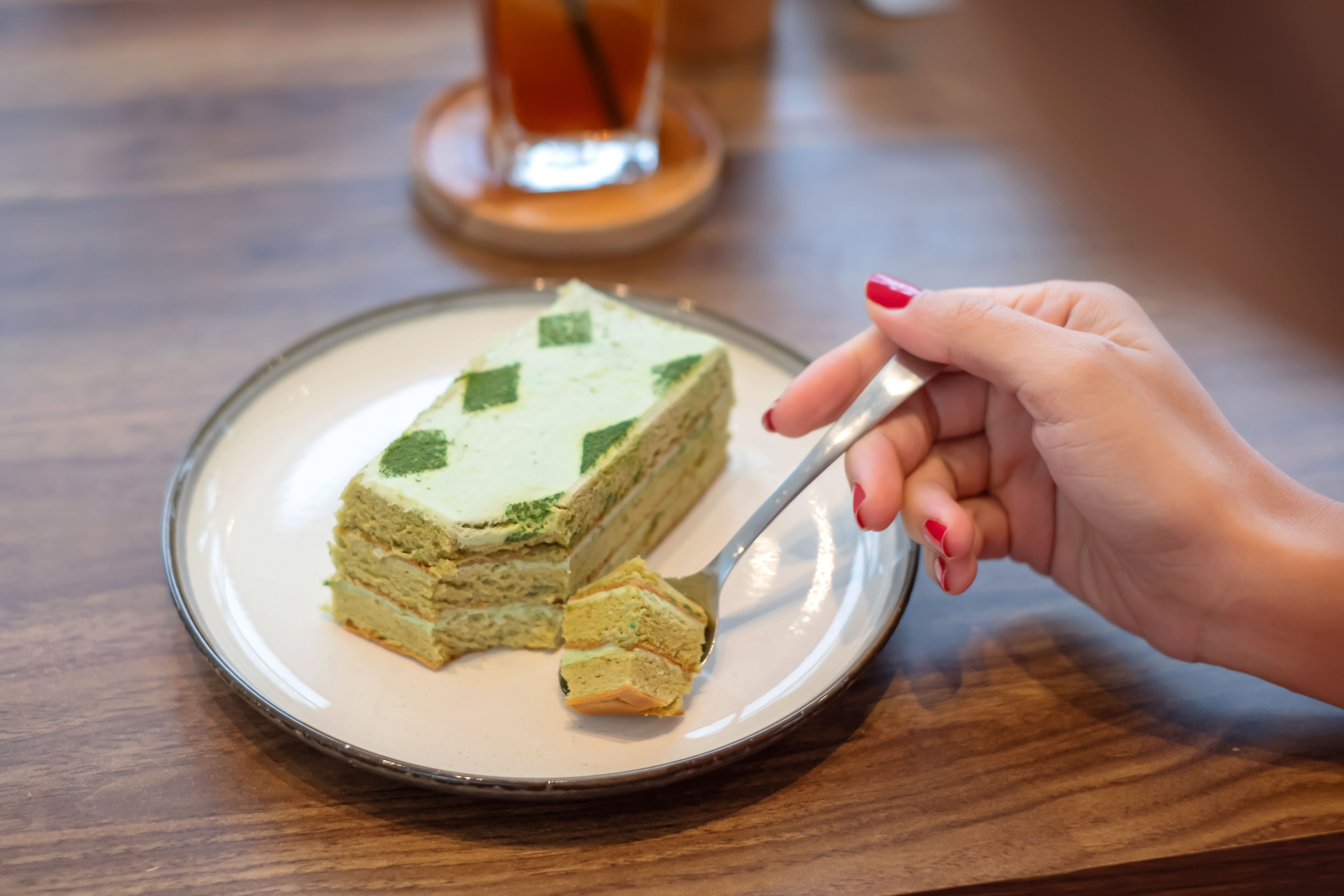 Unrecognizable Chinese Woman Eating Matcha Cake in a Cafe