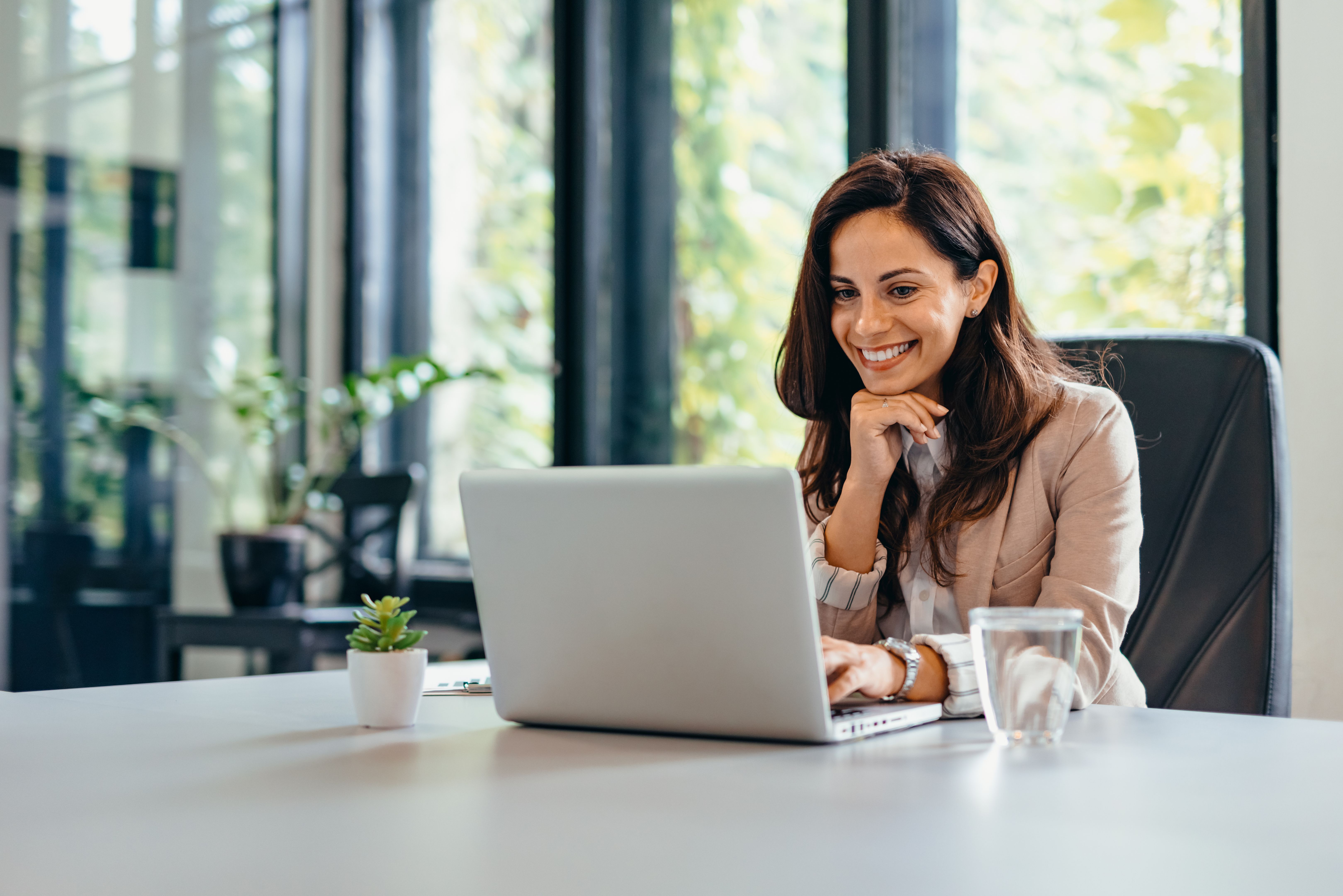 Professional woman at desk using laptop and sitting in modern office.