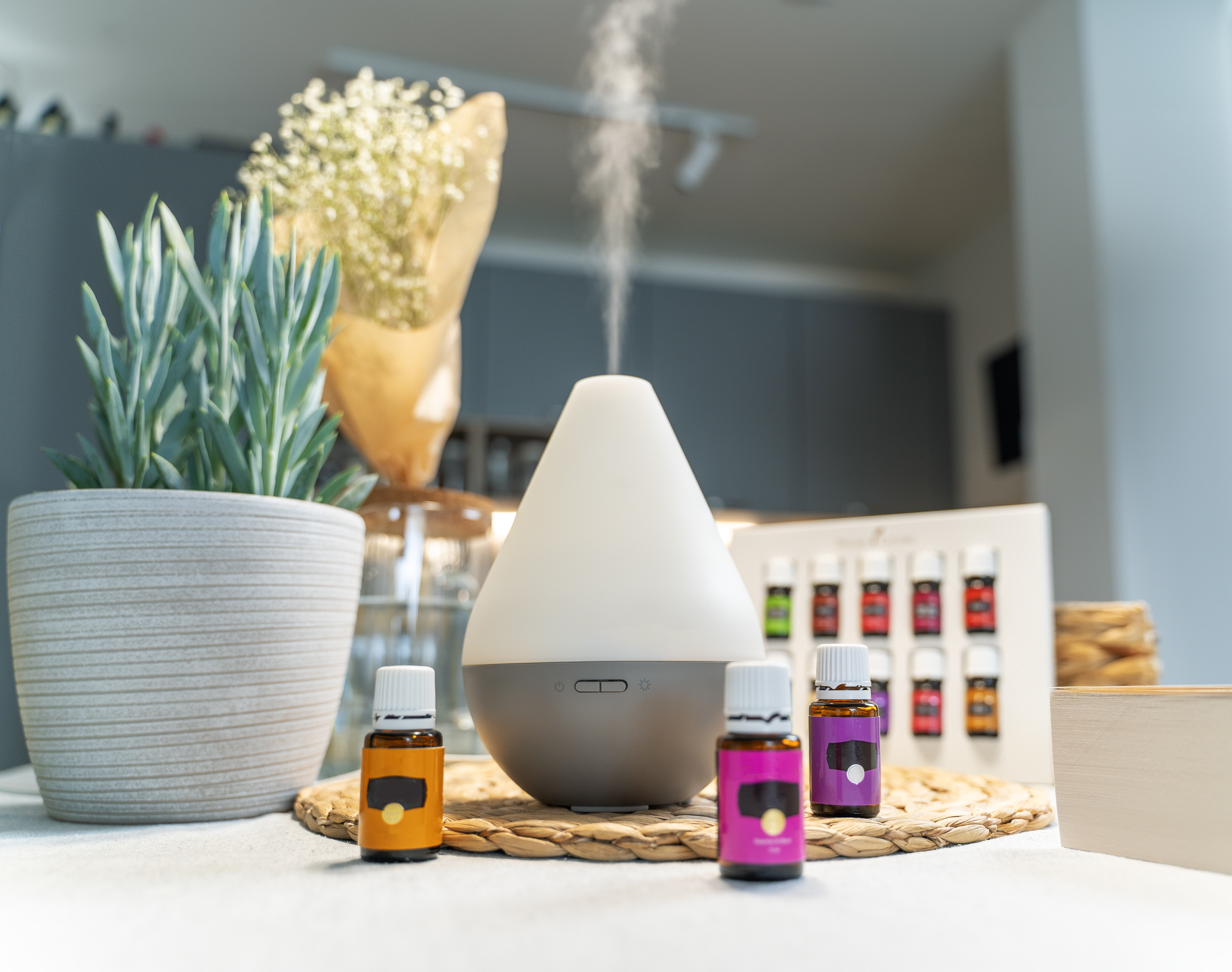 Air diffusor on dinning table with bottles with essential oils next to it, cleaning the air