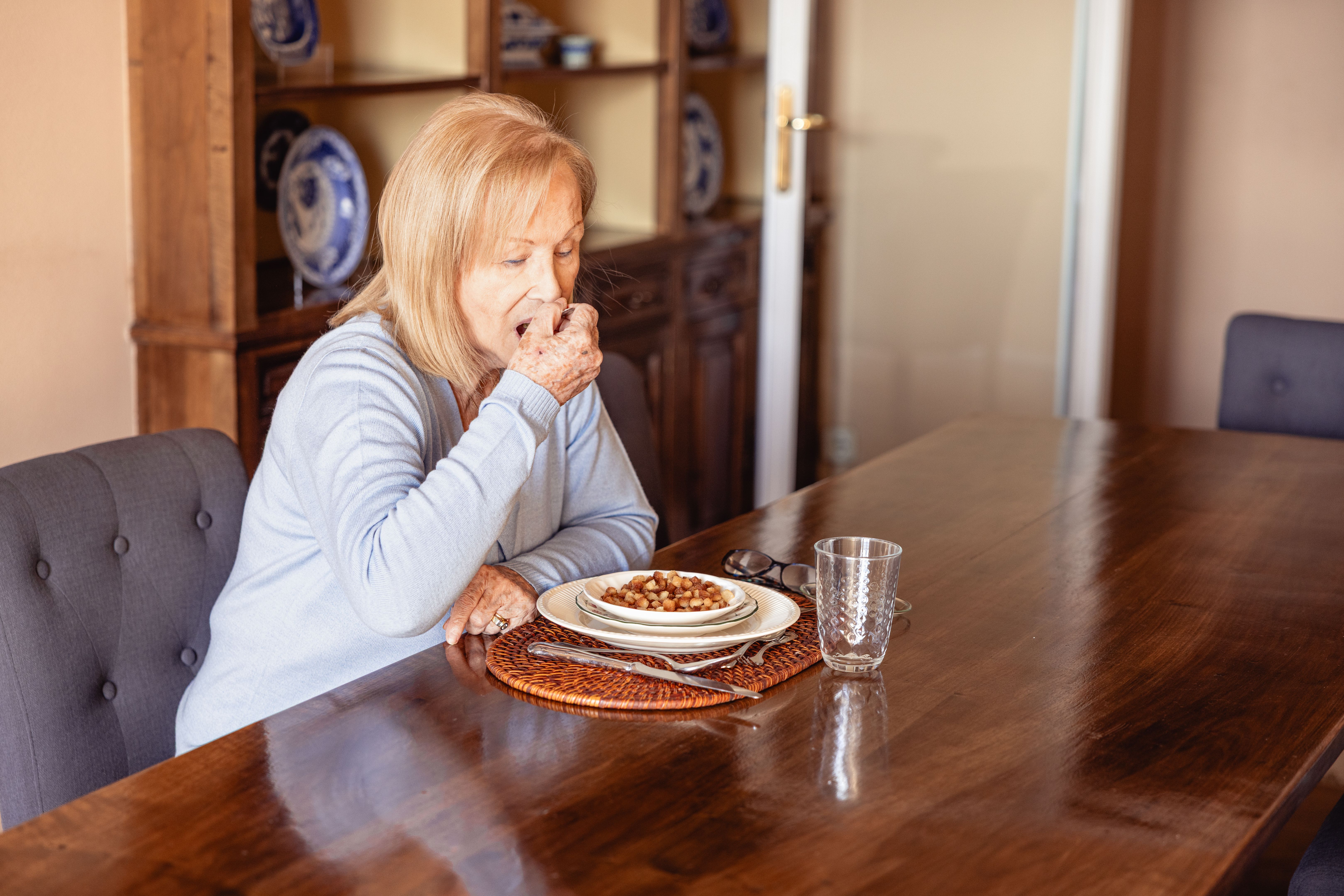 Senior woman eating independently in elegant table setting Senior woman eating independently in elegant table setting