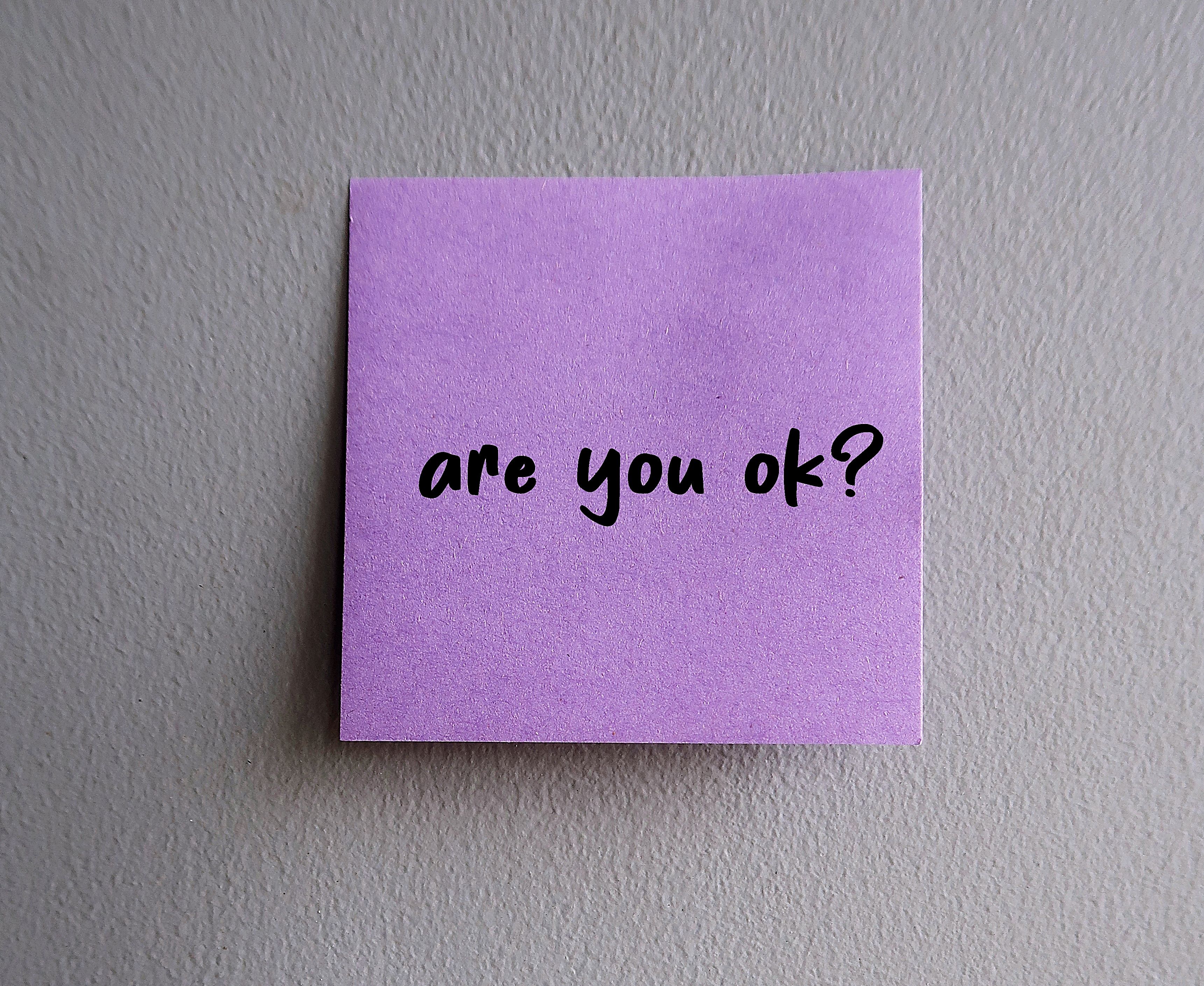 Purple note on a wall with handwritten text: are you ok?
