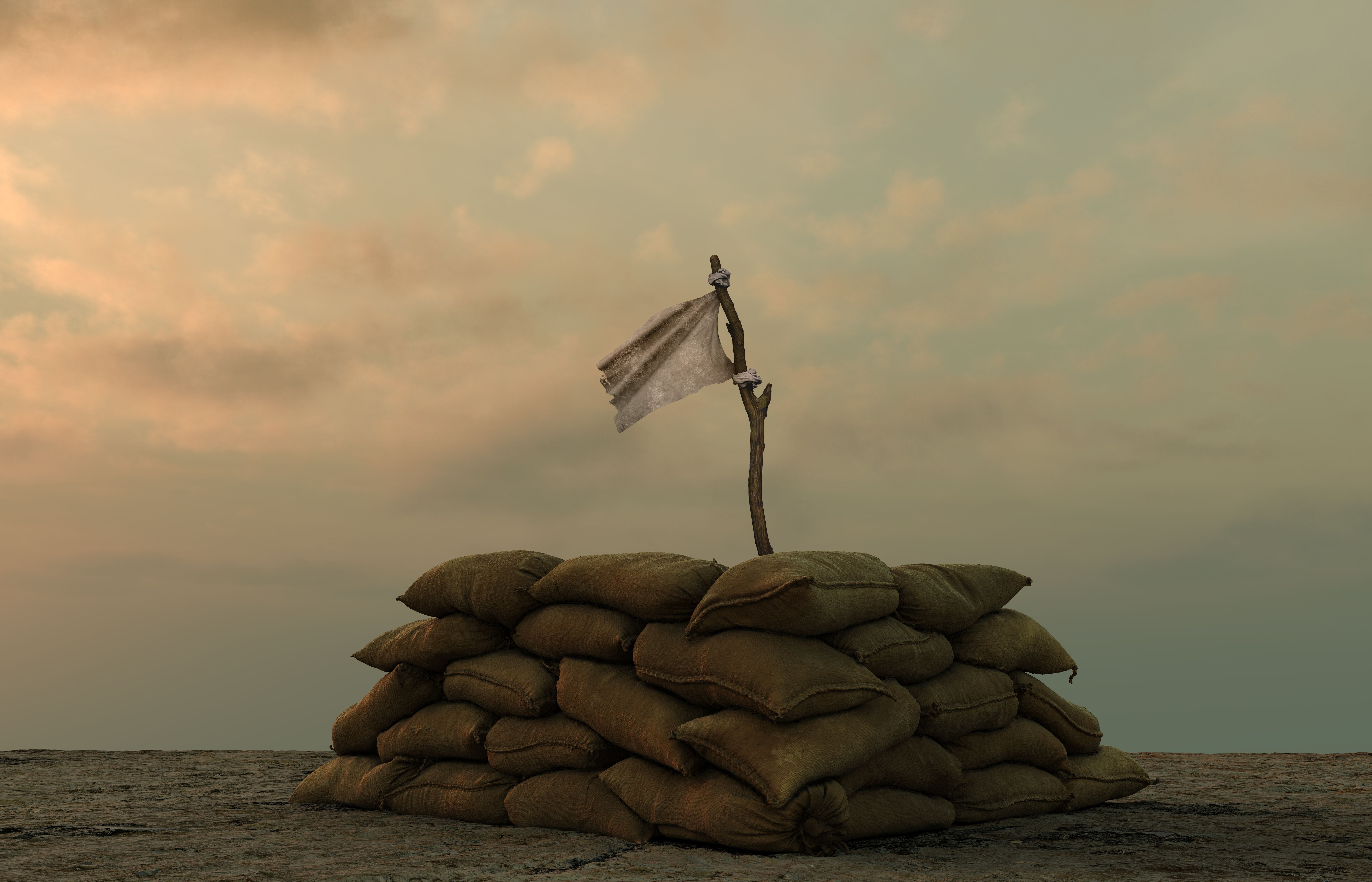 white flag behind military sand bags against sullen sky