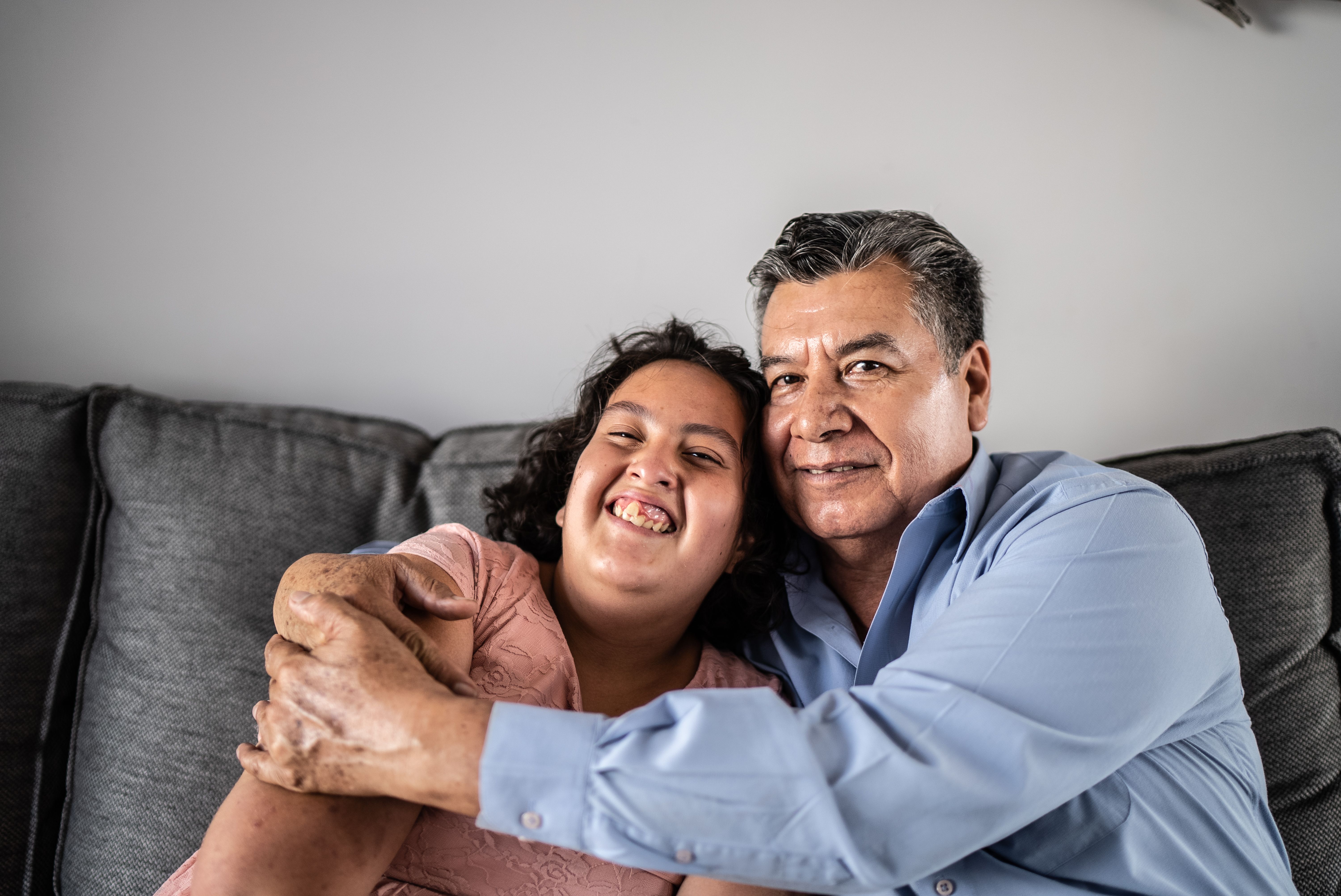 Portrait of father and psychomotor Intellectual disability daughter sitting on the sofa at home