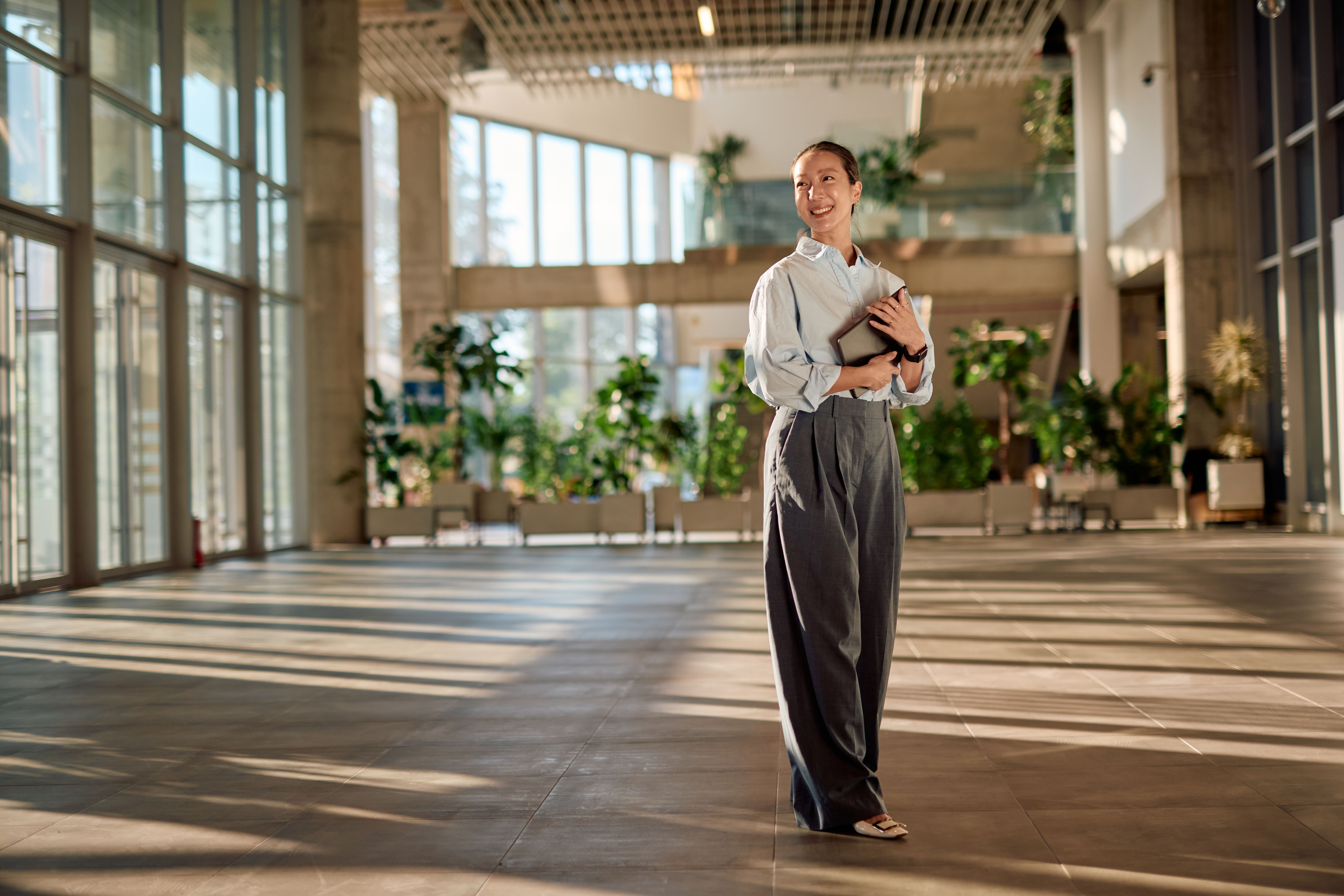 Young Asian businesswoman holding a notebook and smiling in a modern office building