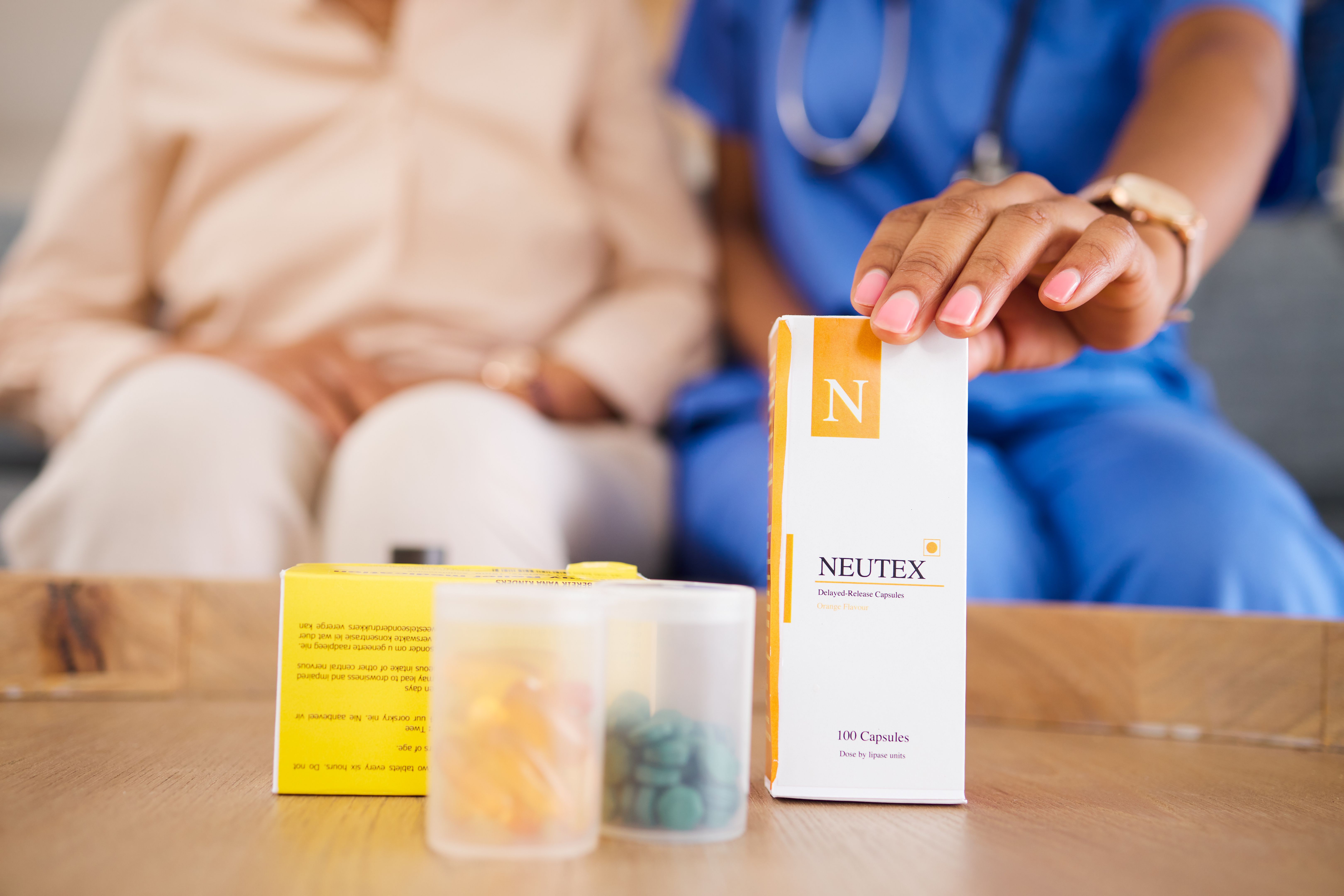 Box, hands and medicine with doctor, patient and table in home for wellness, healthcare and advice. Medic, pills and package in consultation, helping and pharmaceutical product for health in house