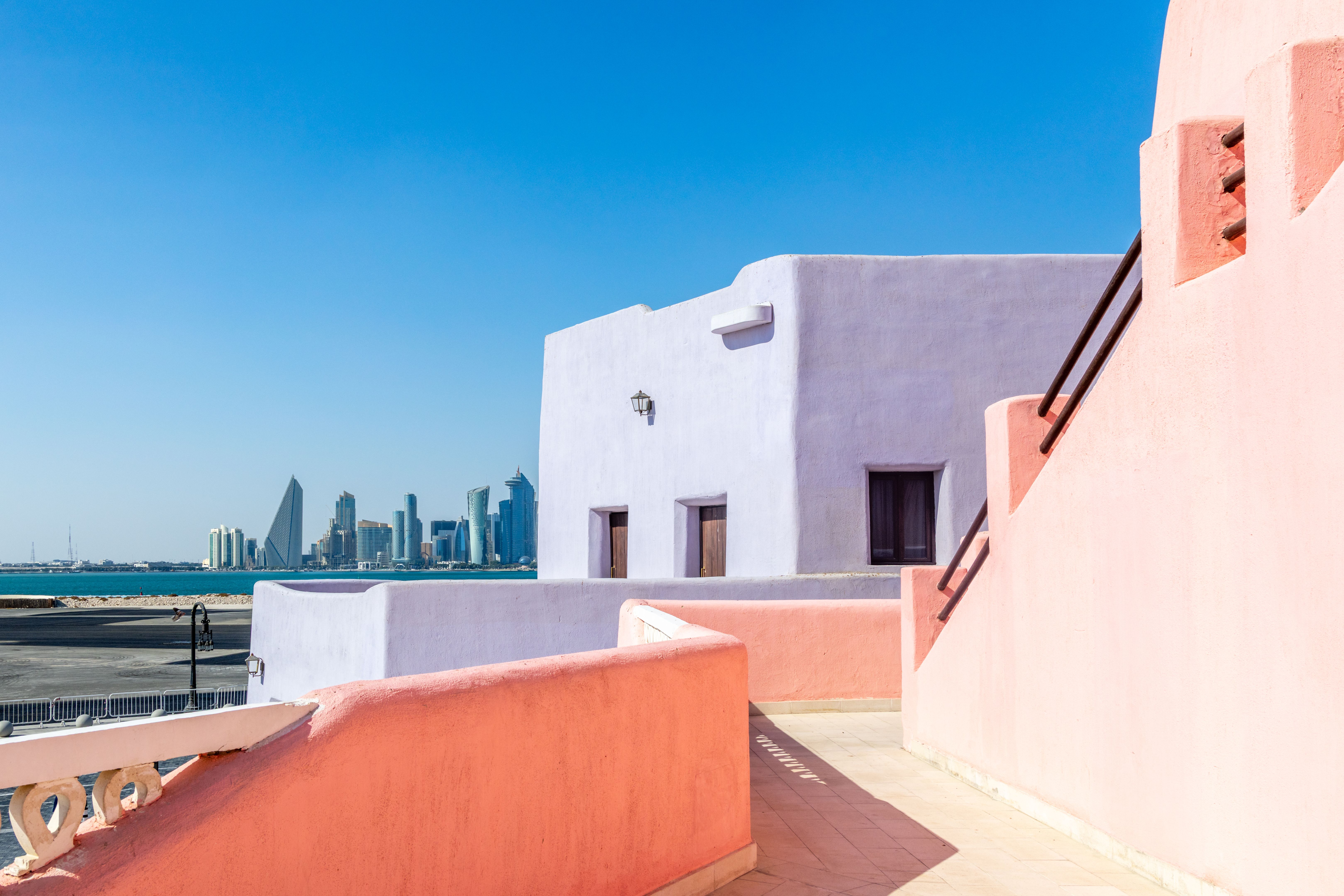 Colorful Mina village district street with arab traditional shaped buildings and modern downtown in the background, Doha, Qatar