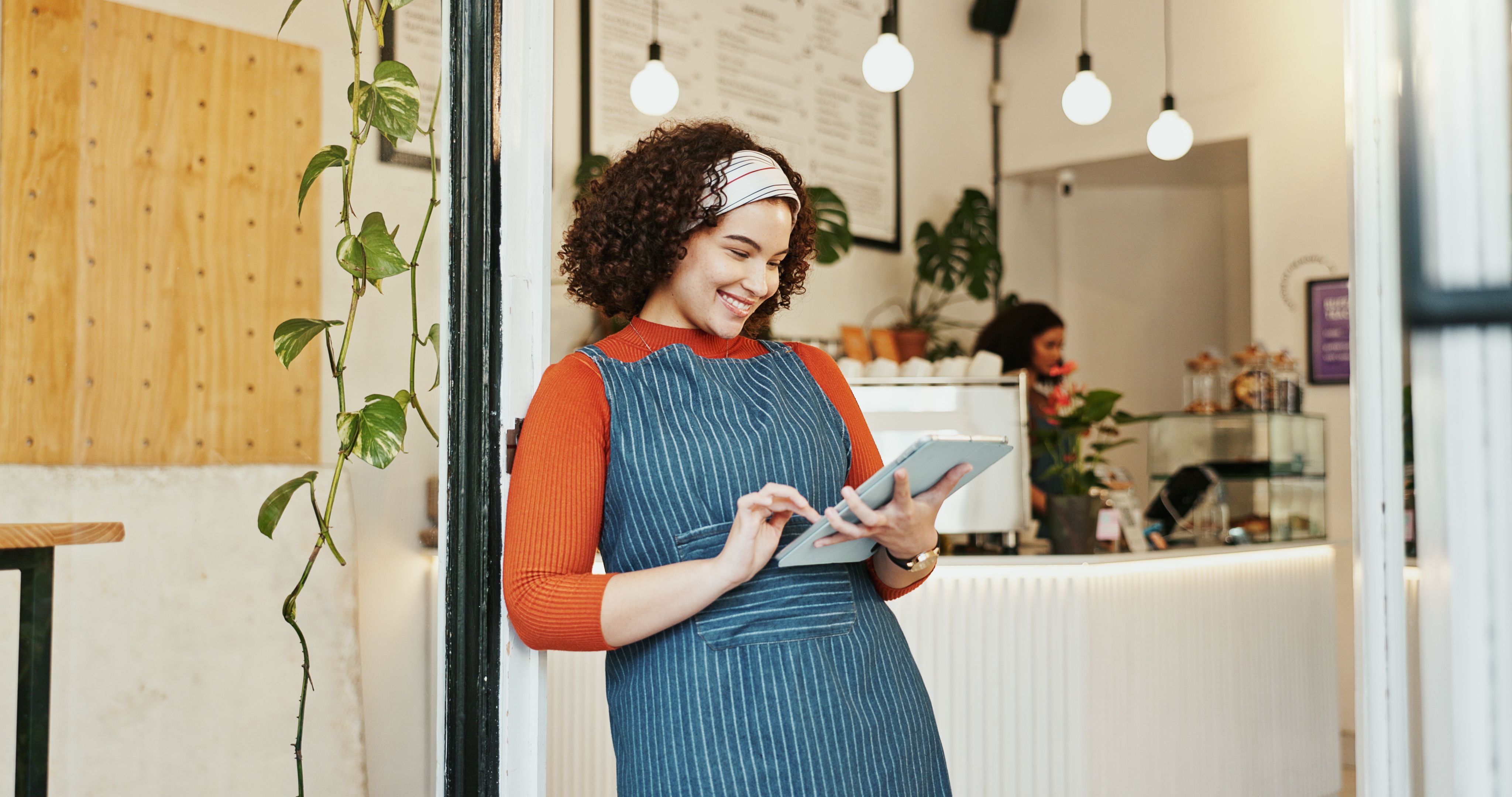 Small business, woman searching and tablet in cafe, happy employee and online inventory or website order. Hospitality, coffee shop and doorway for idea for customer service, waitress and restaurant
