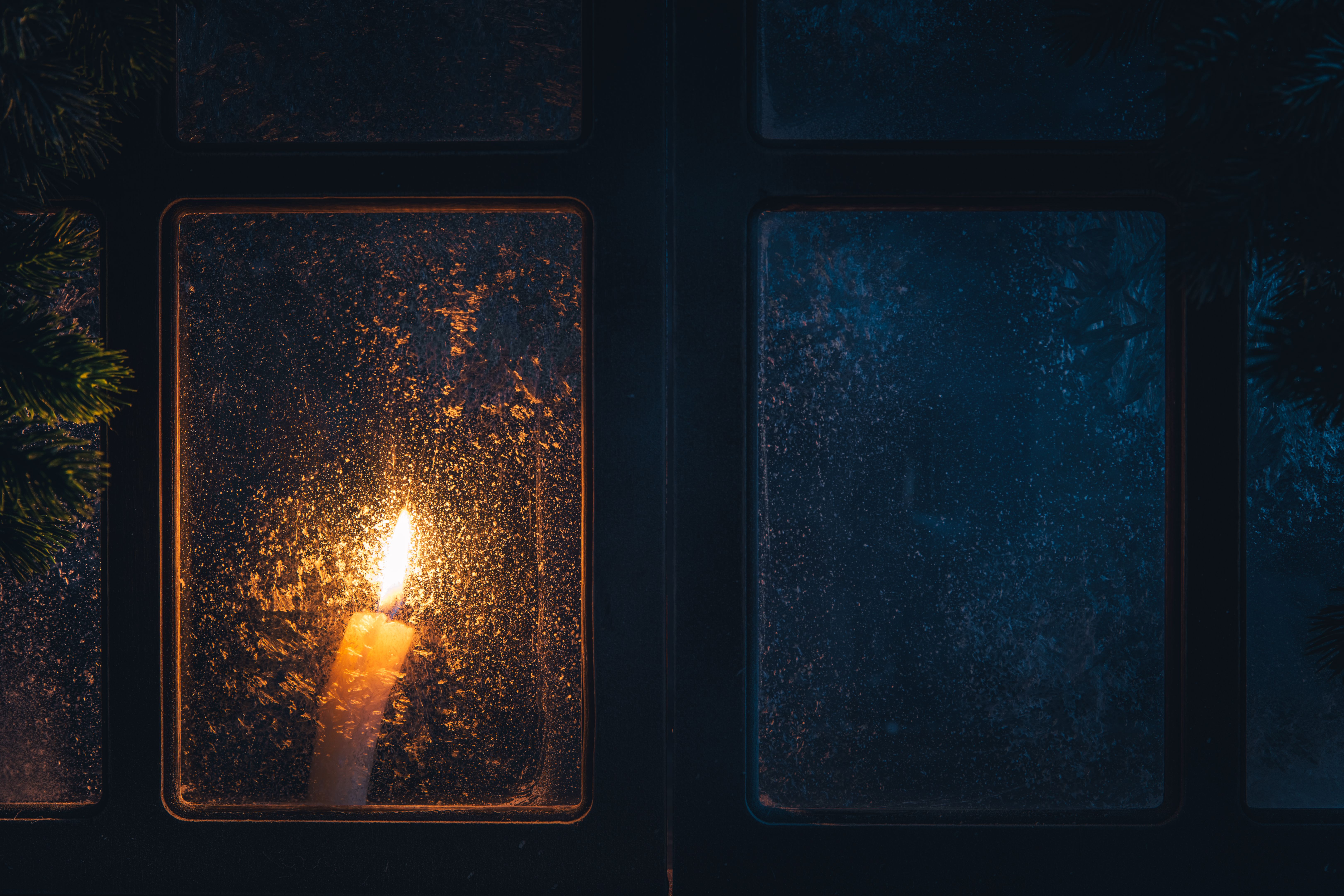 Christmas, new year, winter composition. Candle behind a frozen window Christmas, new year, winter composition. Candle behind a frozen window