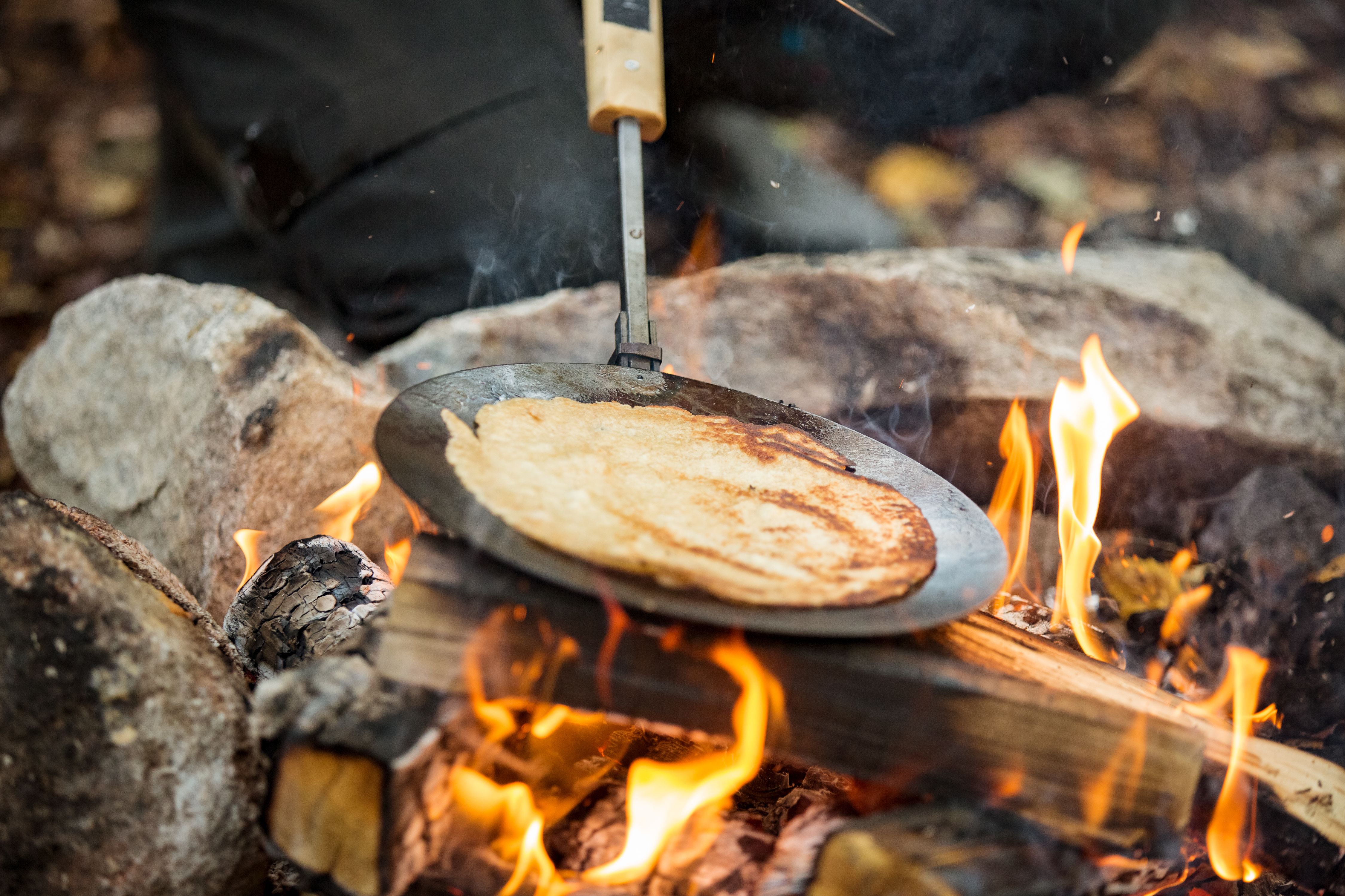 Man and woman making pancakes on campfire