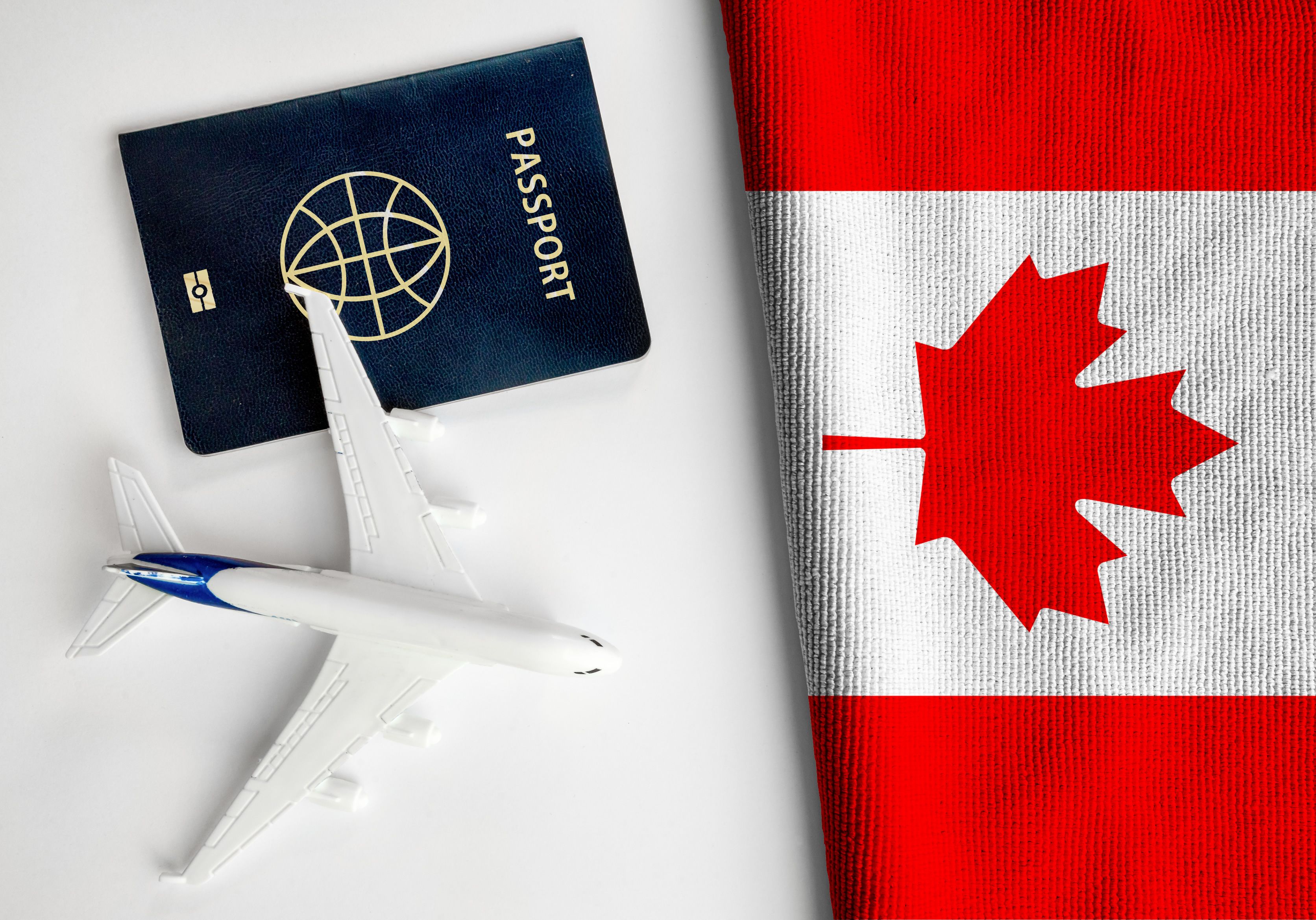 Flag of Canada with passport and toy airplane.