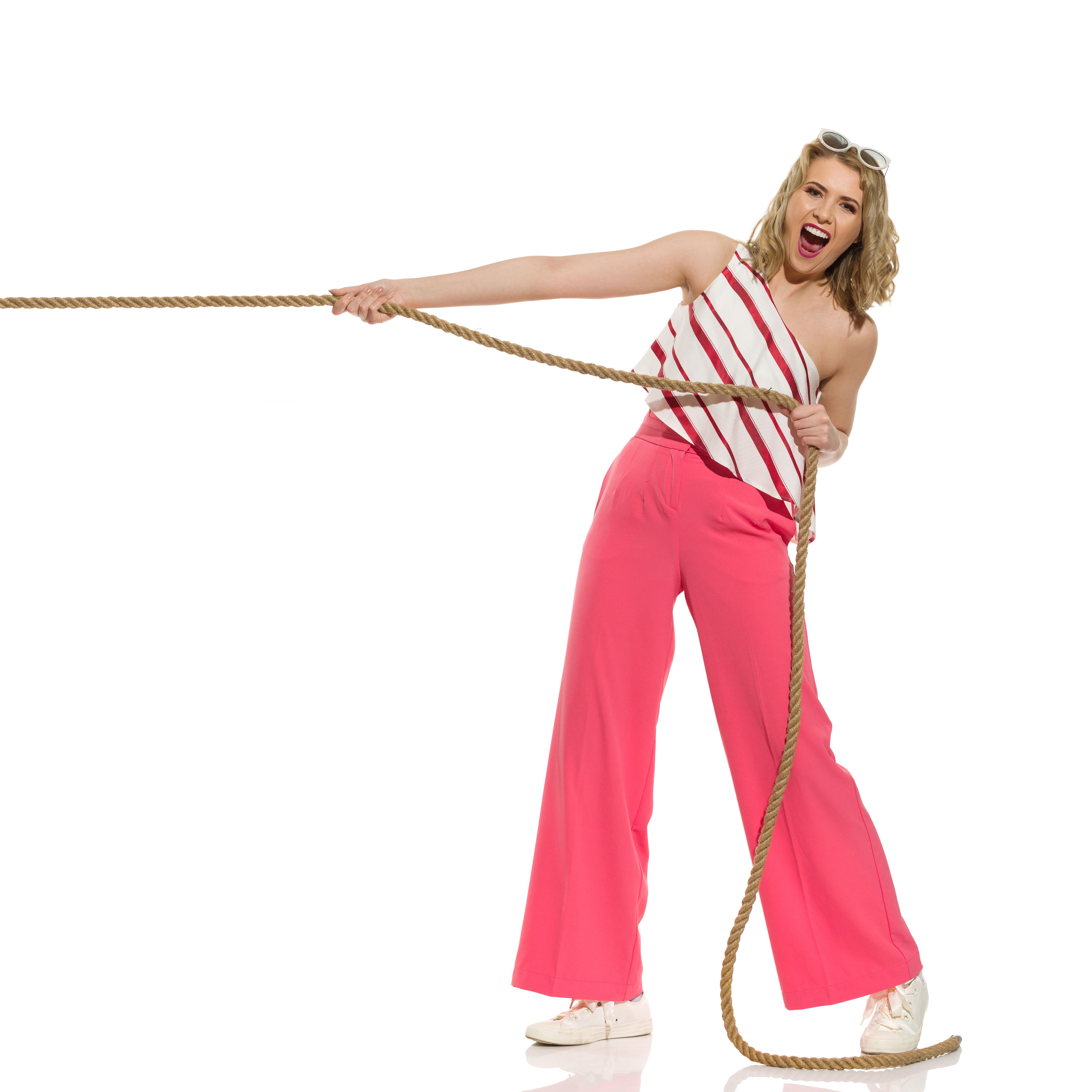Excited young woman is pulling the rope and shouting. Full length isolated.